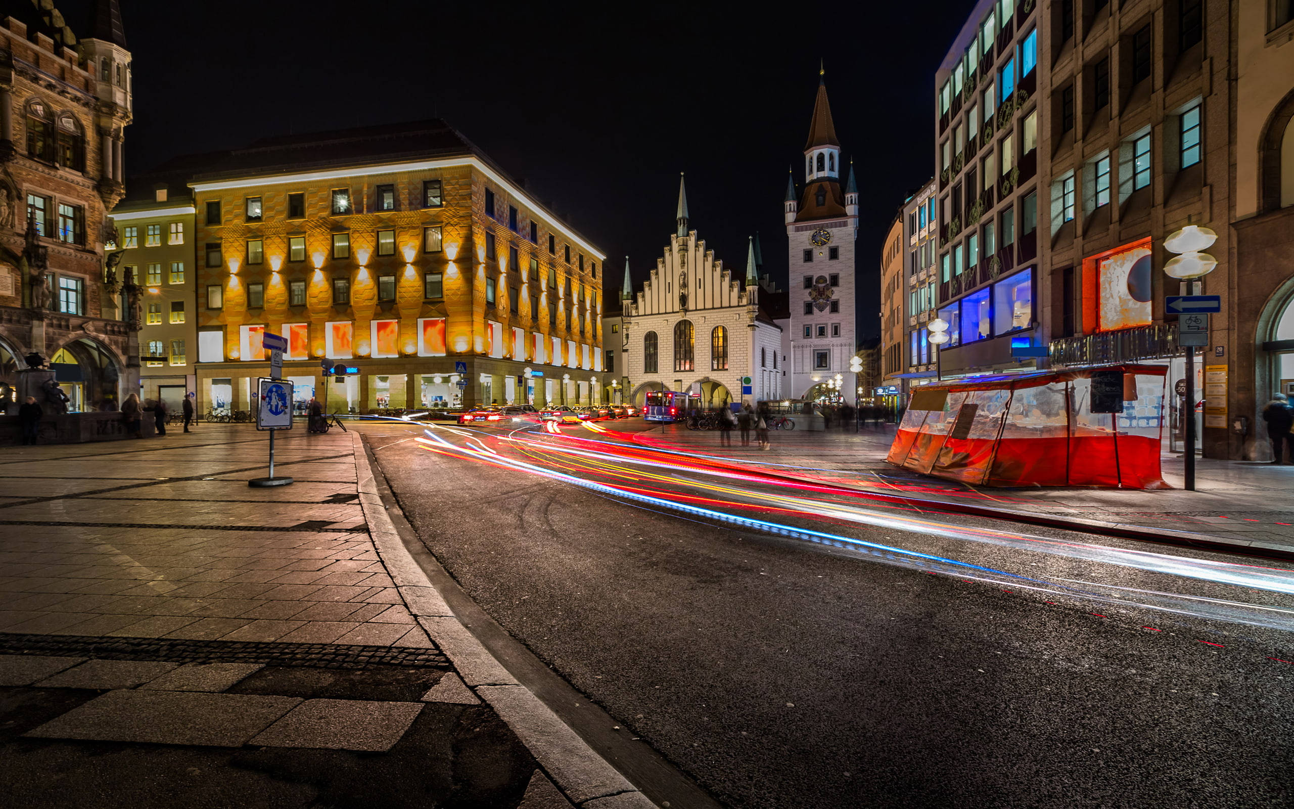 Munich 桌布 壁紙 — 充滿活力的夜景城市景觀，汽車駛過歷史建築和鐘樓時留下的光軌。
