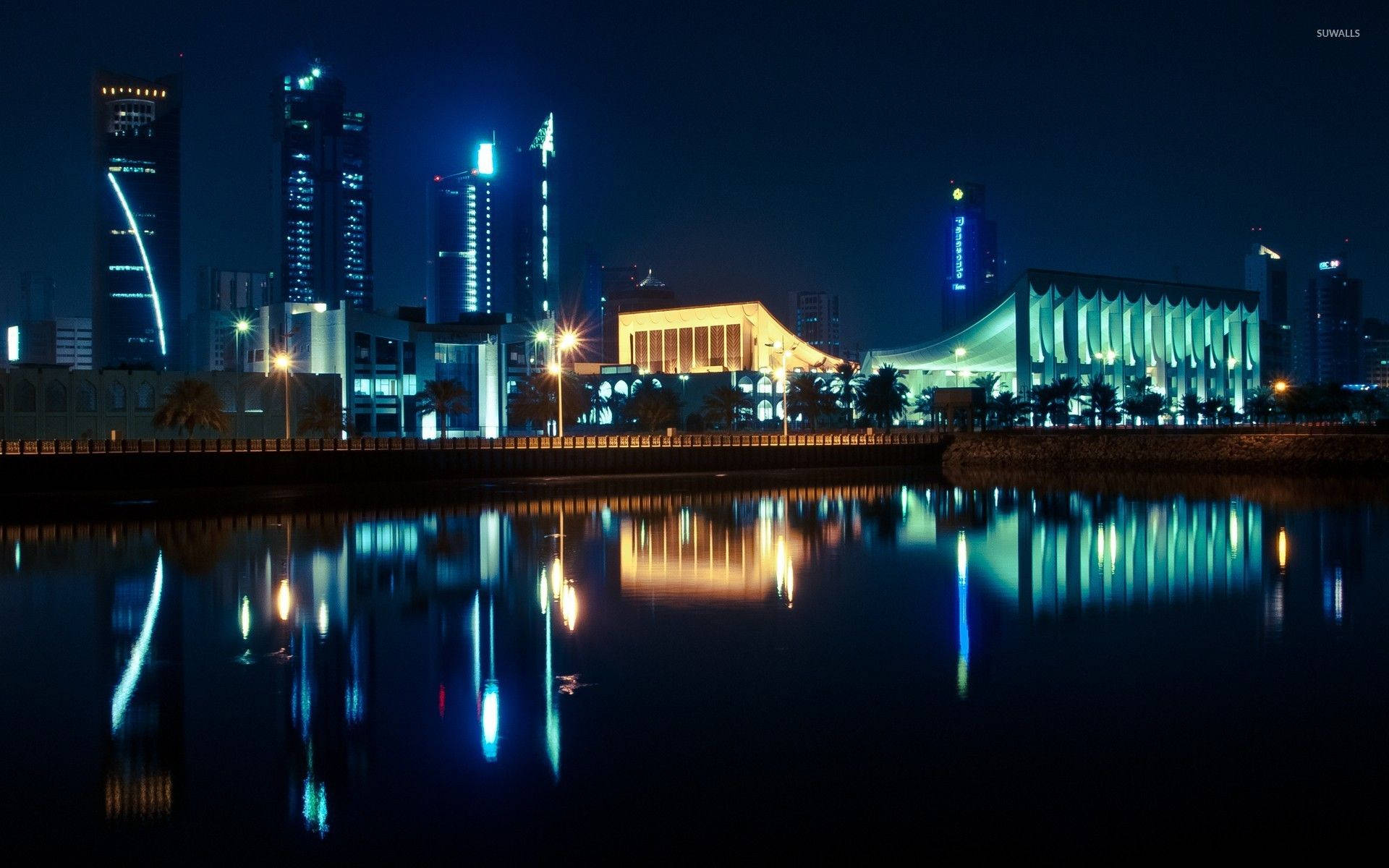 科威特 桌布 壁紙 — 充滿活力的夜景城市景觀，燈火通明的摩天大樓和現代建築倒映在平靜的水面上。