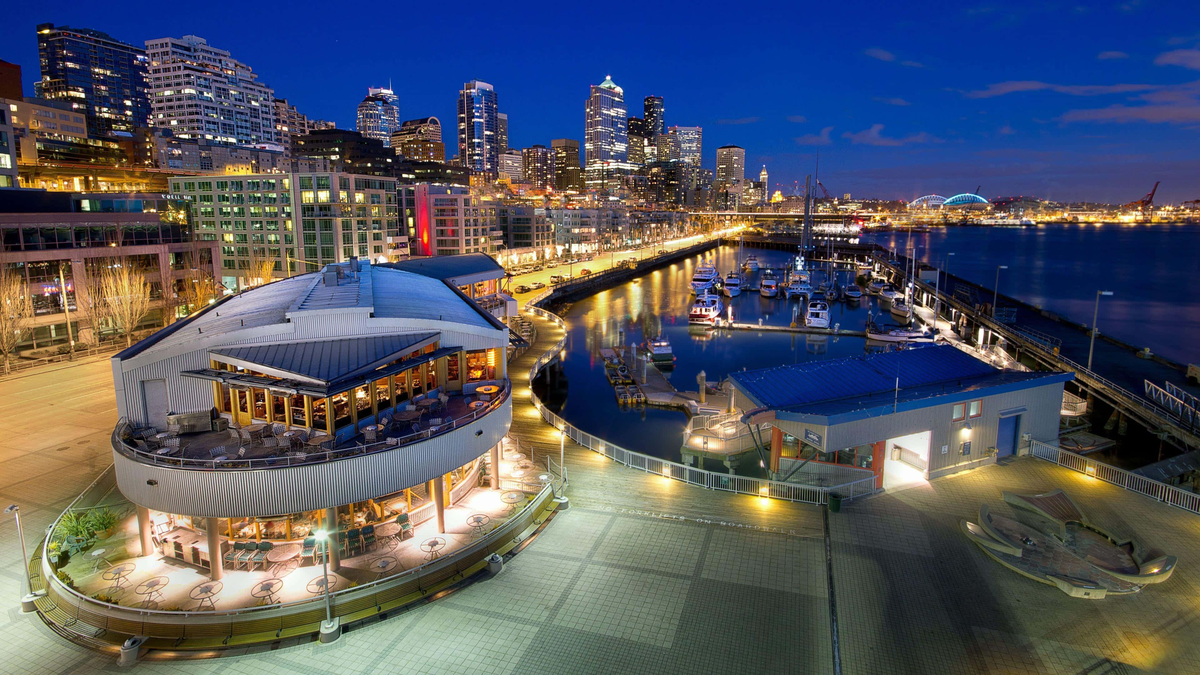 Harbor 桌布 壁紙 — 充滿活力的夜景城市景觀，設有現代圓形建築，俯瞰著停滿船隻的碼頭和閃爍的天際線。