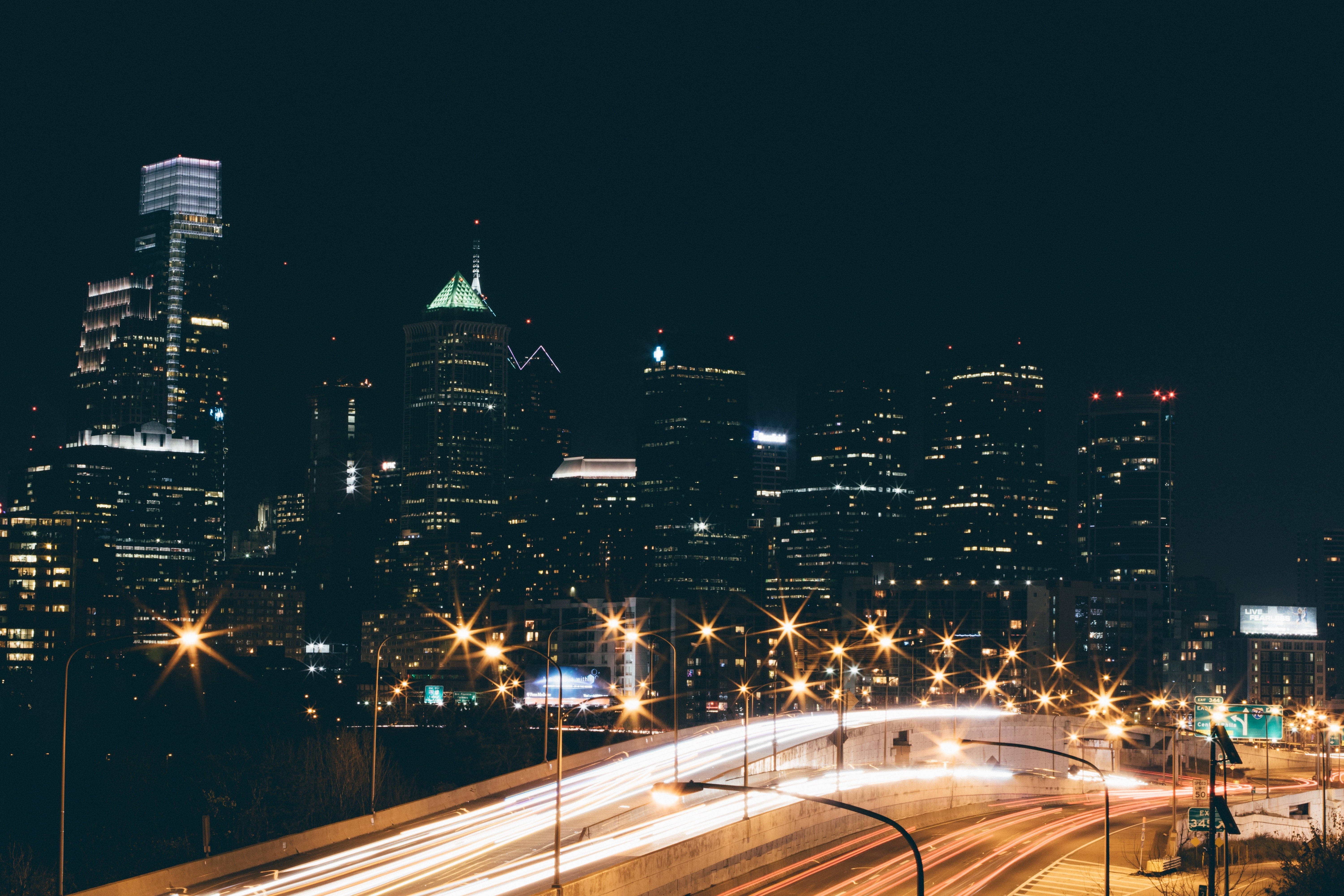 Philadelphia 桌布 壁紙 — 充滿活力的夜景城市景觀，閃爍的摩天大樓和彎曲高速公路上的車流光跡。