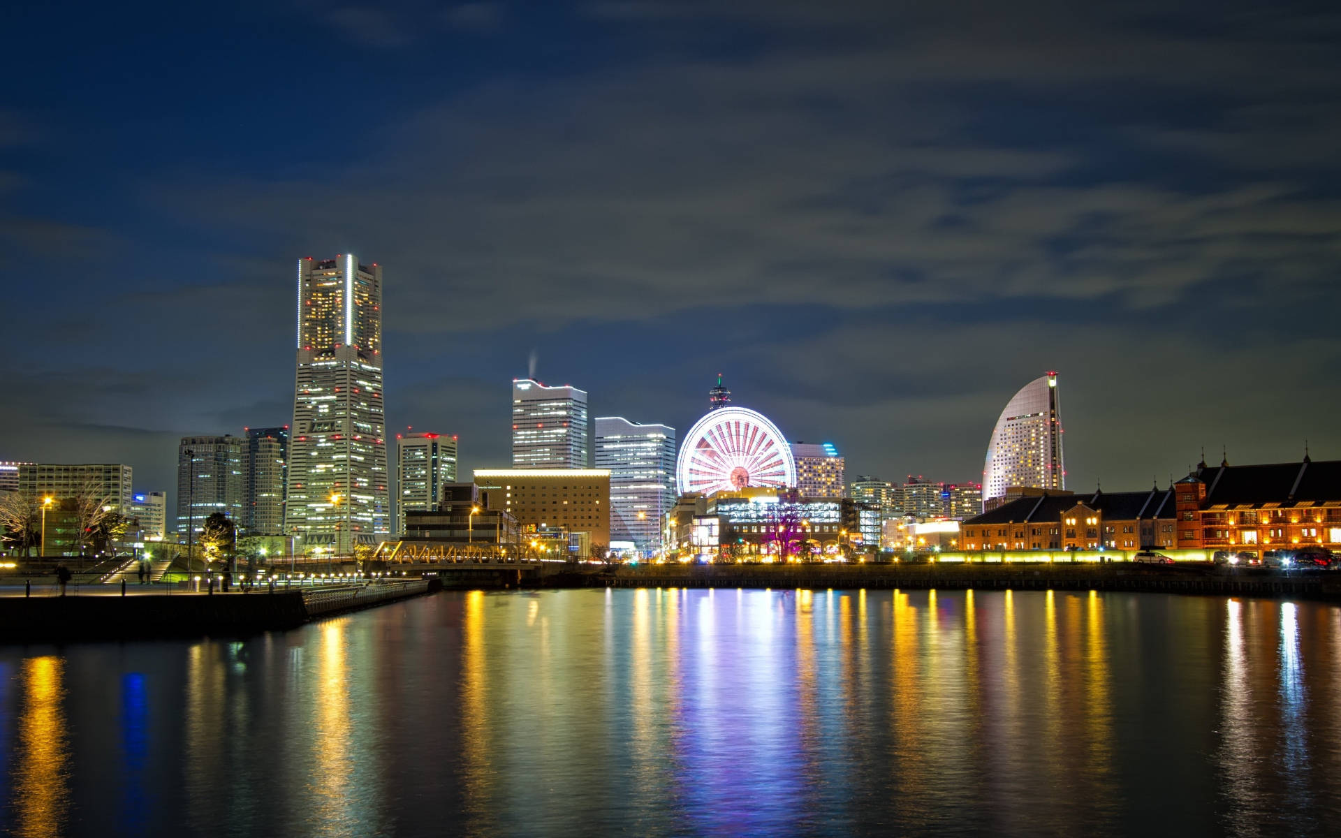 Yokohama 桌布 壁紙 — 充滿活力的夜景城市景觀，閃爍的摩天大樓和色彩繽紛的摩天輪倒映在平靜的水面上。