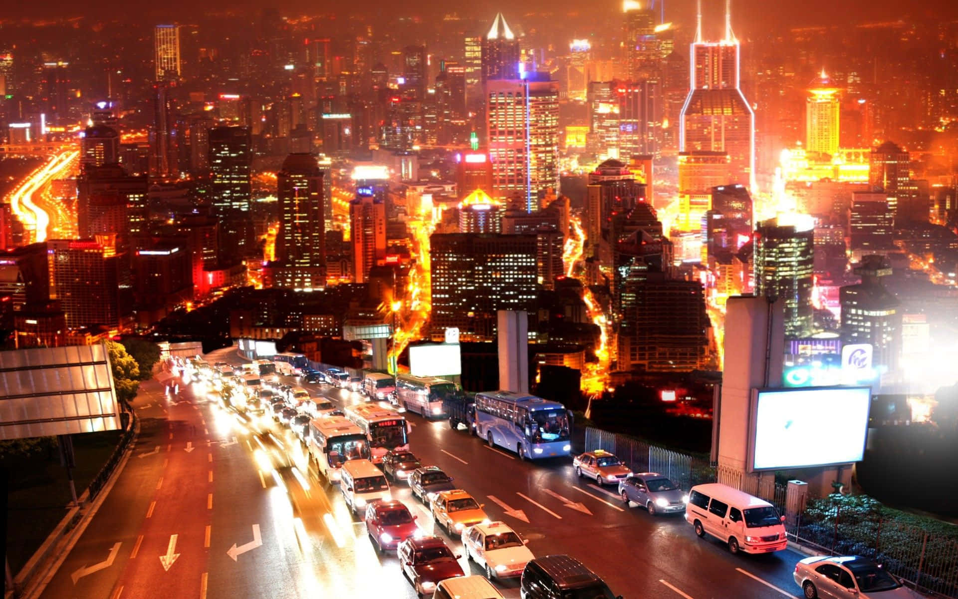 Urban 桌布 壁紙 — 充滿活力的夜景城市景觀，閃爍的摩天大樓和流動的交通燈光點亮了繁忙的高速公路。
