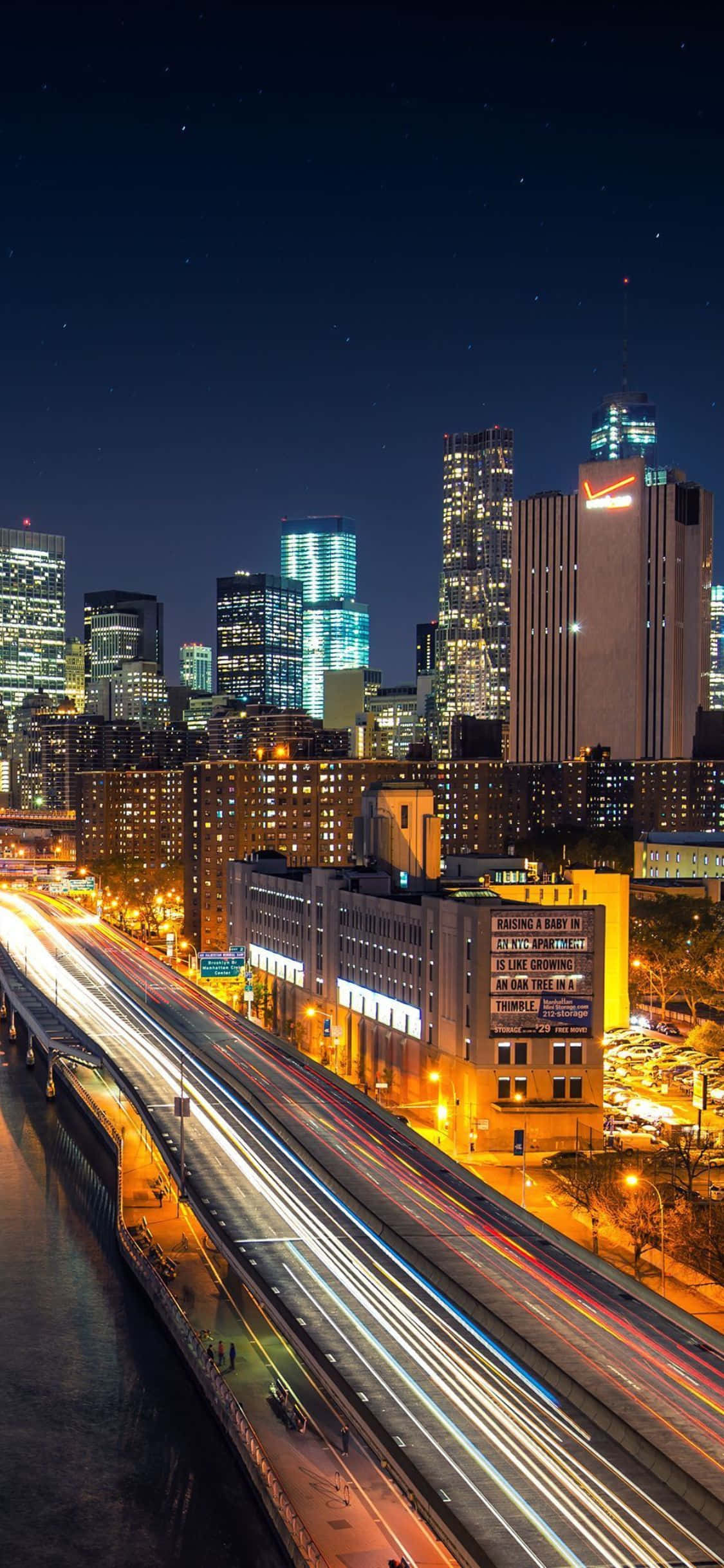 iPhone Xs Ny City 桌布 壁紙 — 充滿活力的夜景城市景觀，閃爍的摩天大樓和高速公路上車流留下的光軌。