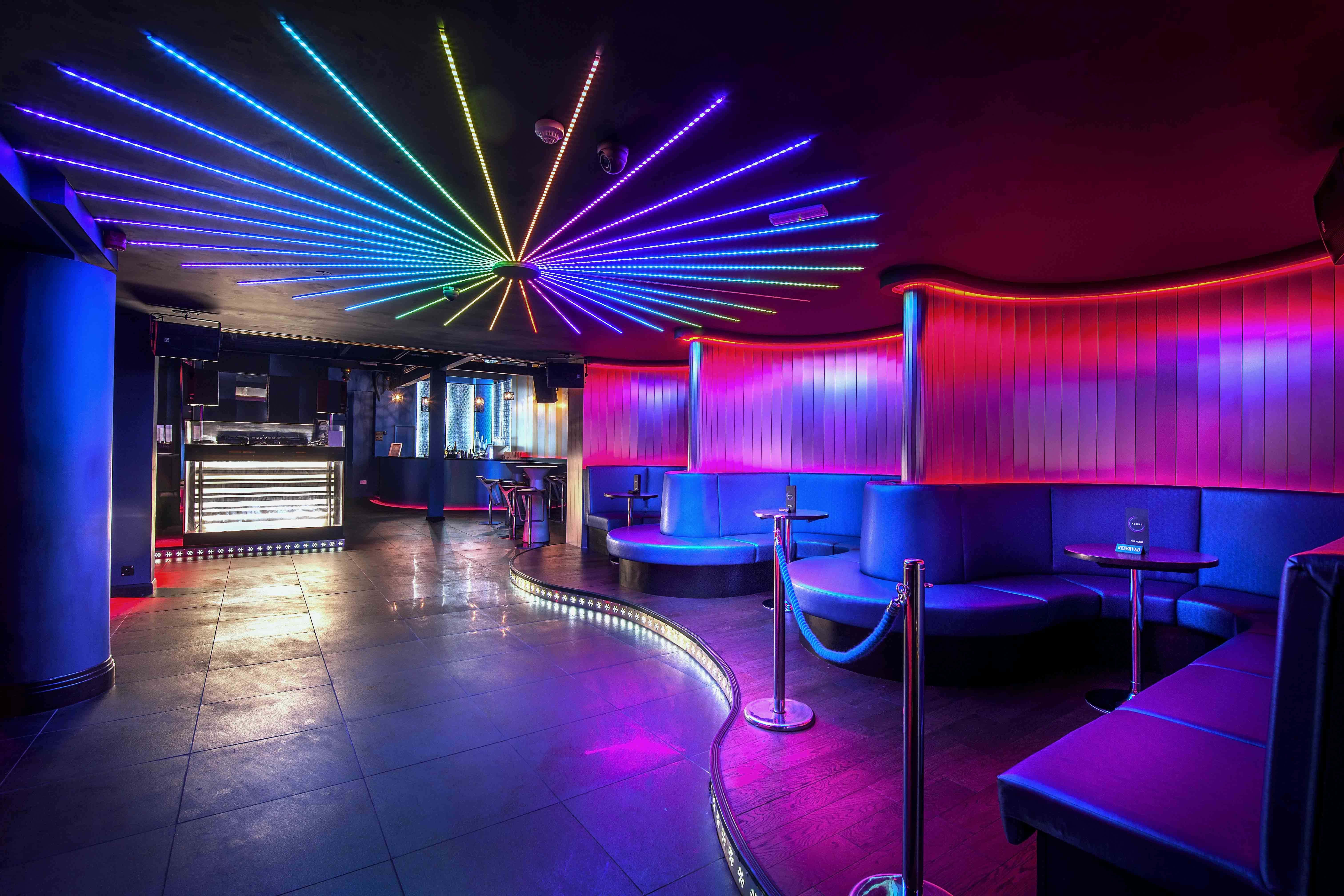 Nightclub 桌布 壁紙 — 充滿活力的夜總會，天花板上散發著霓虹燈光，閃爍著紫藍色的座位區。