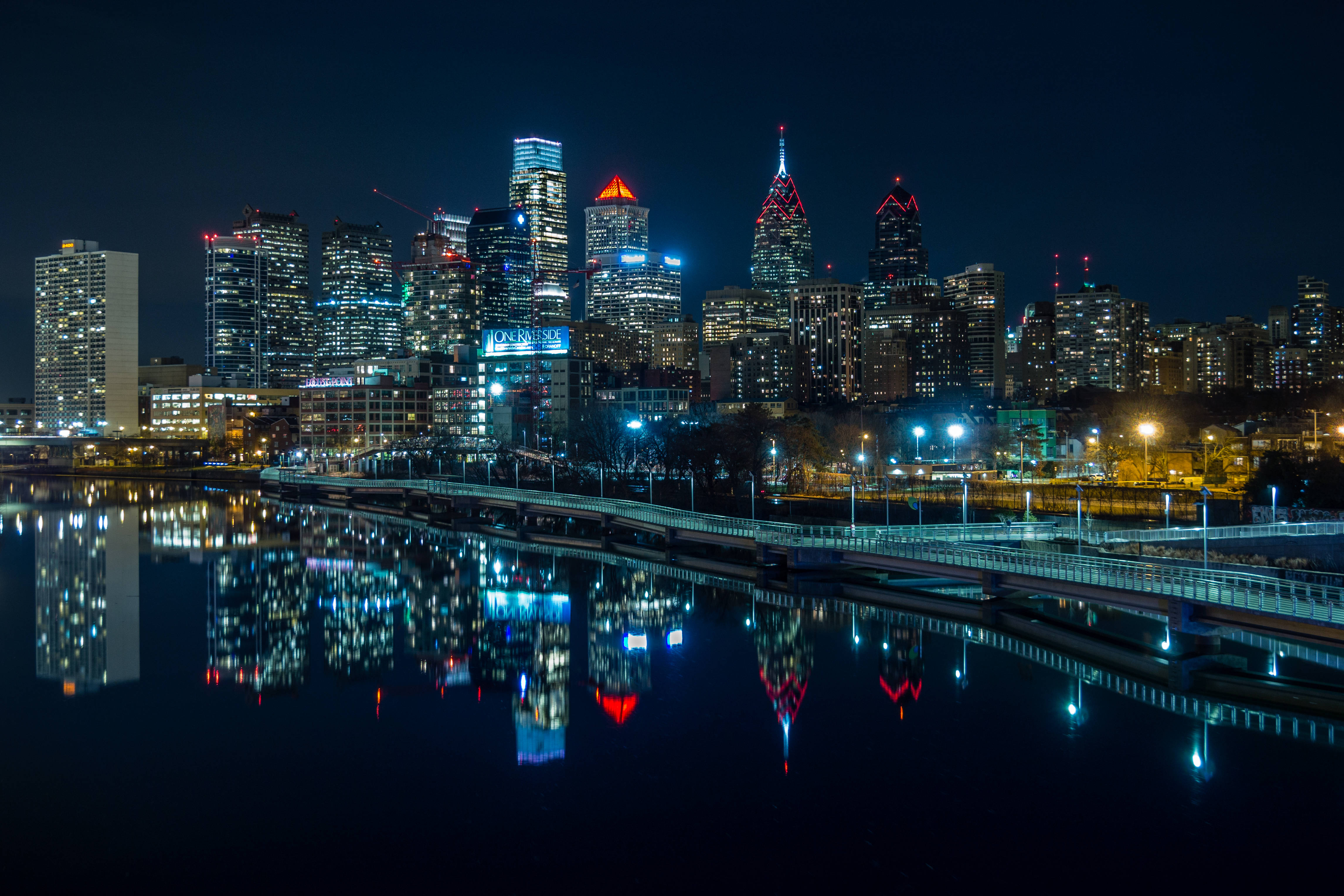 Philadelphia 桌布 壁紙 — 充滿活力的夜間城市景觀，摩天大樓在黑暗的天空中閃耀，它們的燈光完美地倒映在下方平靜的水面上。