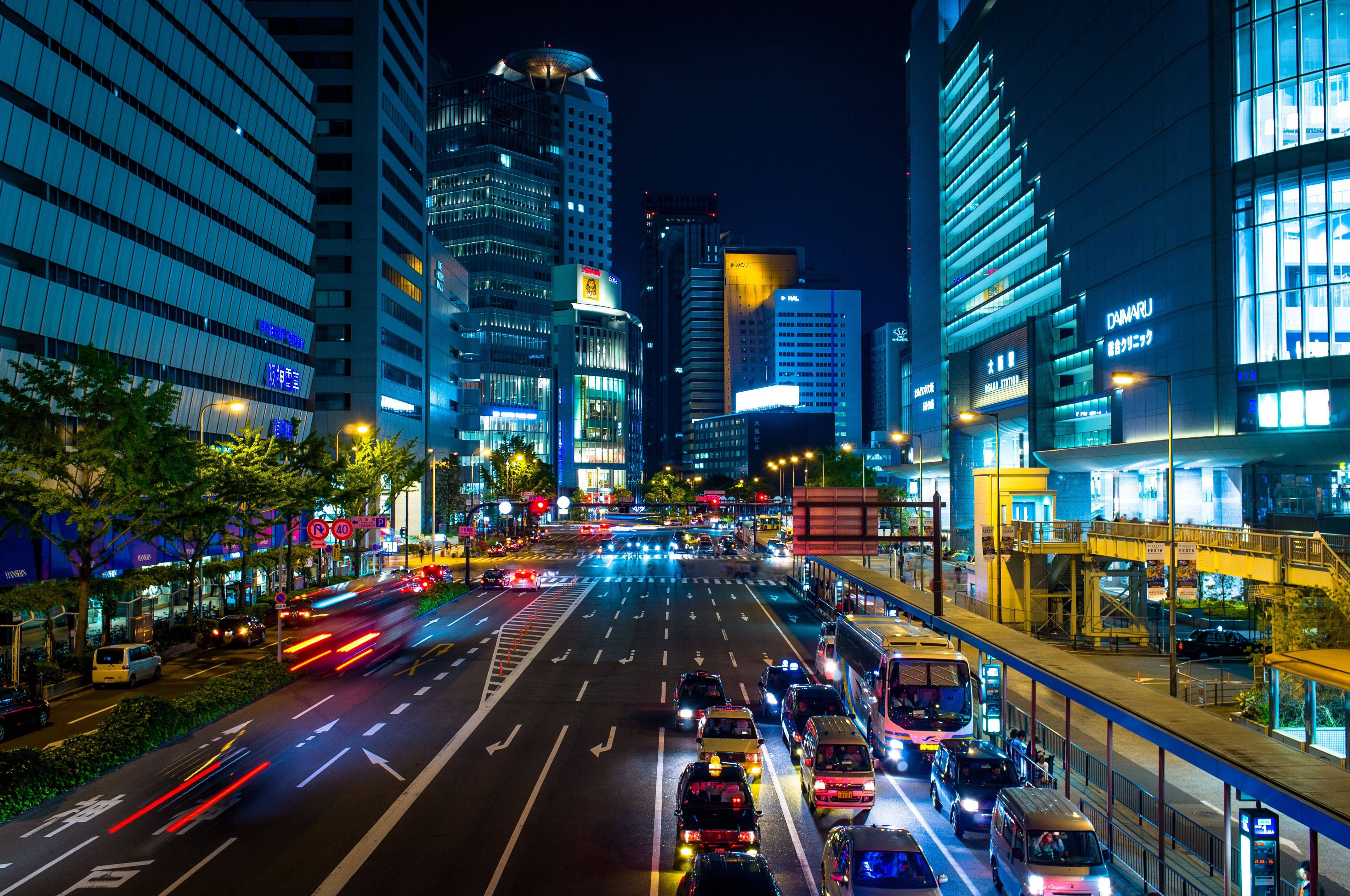 日本 桌布 壁紙 — 充滿活力的夜間城市景觀，有發光的摩天大樓和繁忙城市街道上流動的車燈。