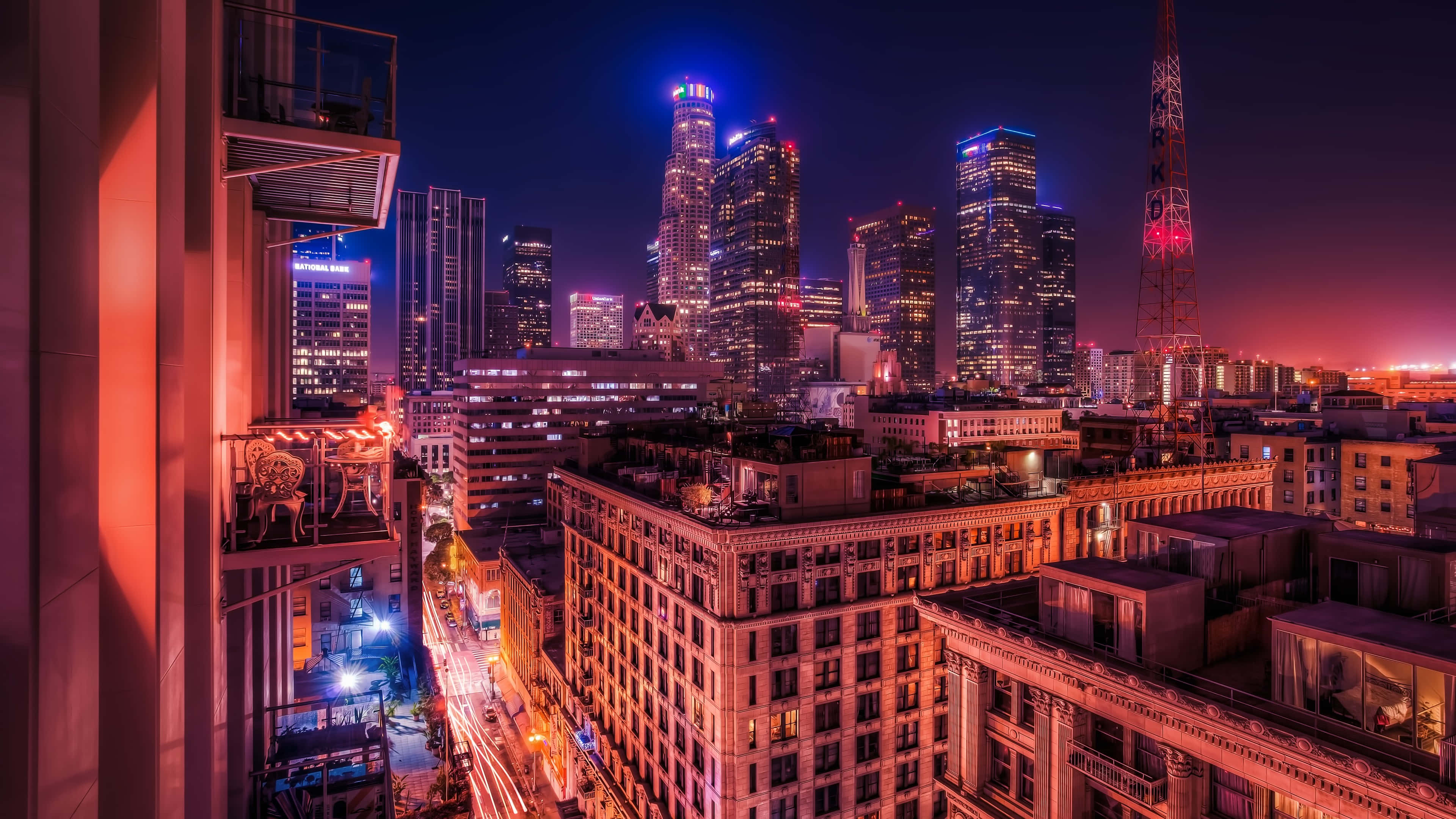 La 桌布 壁紙 — 充滿活力的夜間城市景觀，閃爍的摩天大樓和溫暖的路燈照亮了密集的城市峽谷。