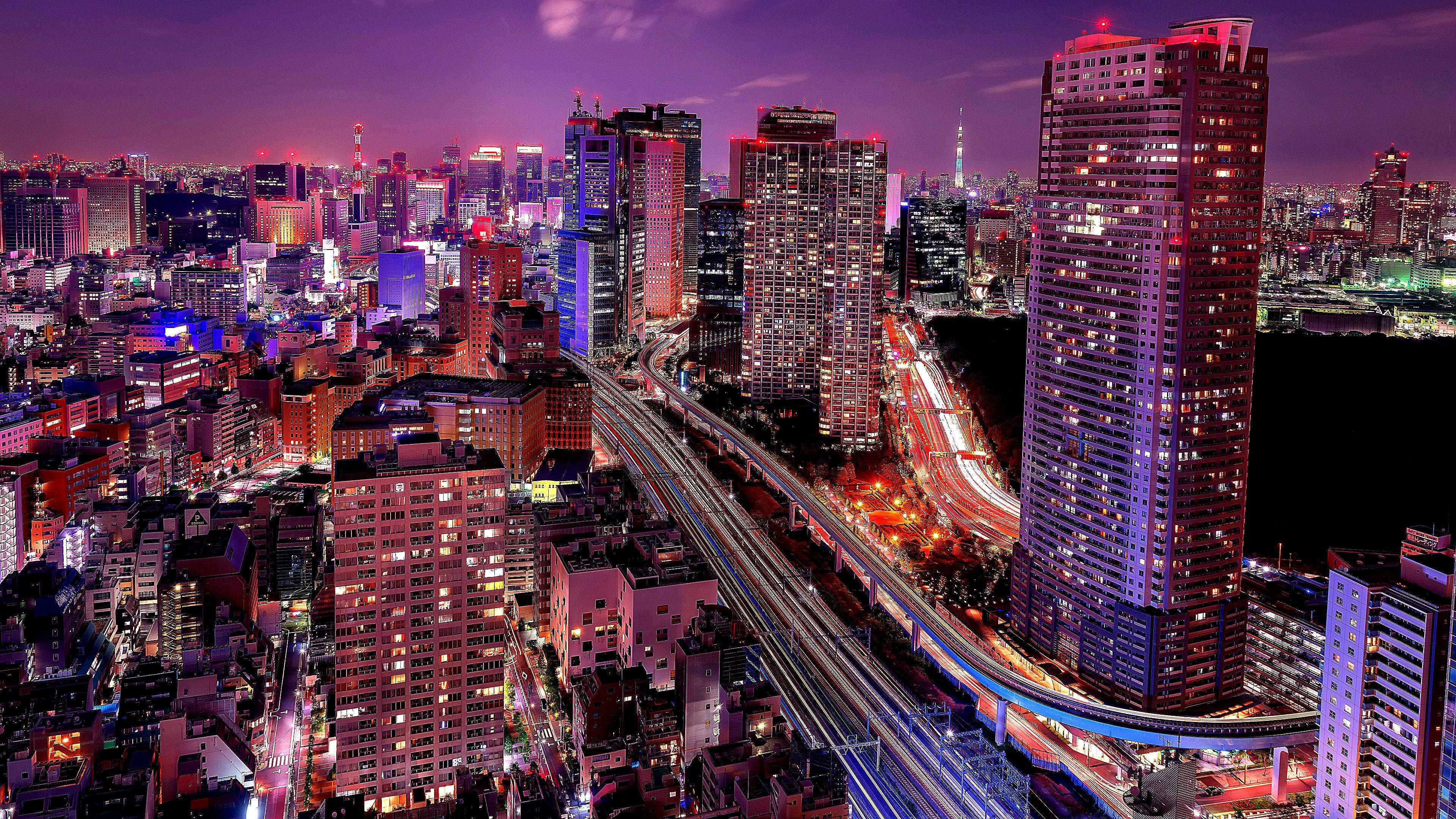 東京 桌布 壁紙 — 充滿活力的夜間城市景觀，閃爍的摩天大樓和高架高速公路上的車流光軌。