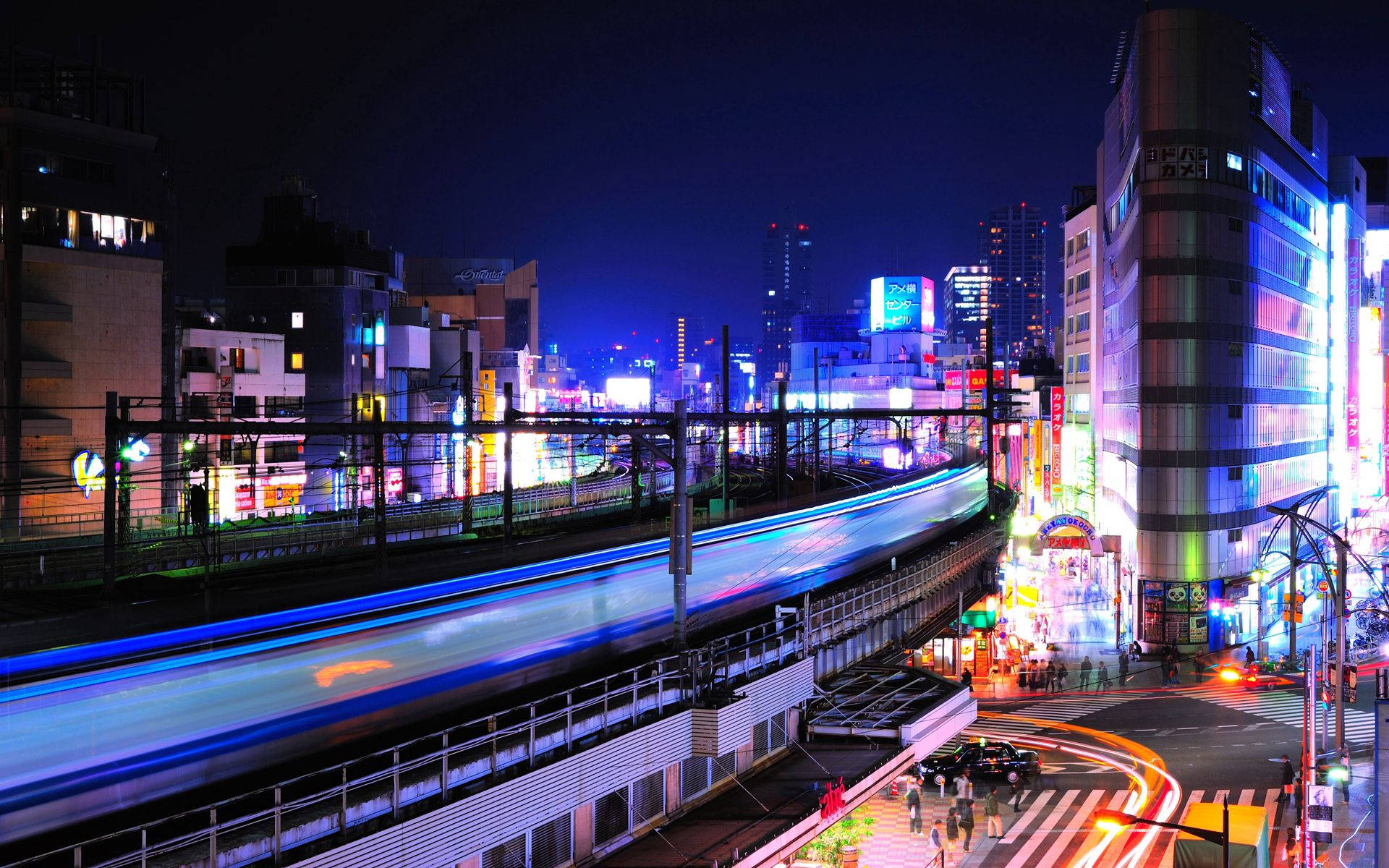東京 桌布 壁紙 — 充滿活力的夜間城市景觀，霓虹燈和火車運動模糊照亮繁華的城市街道。