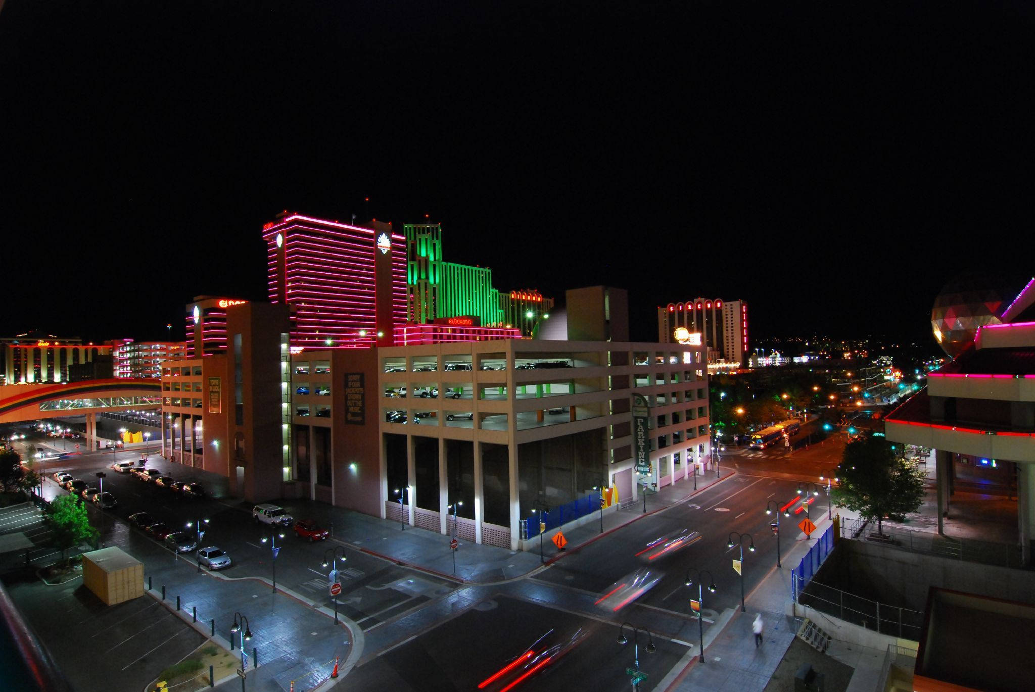 City At Night 桌布 壁紙 — 充滿活力的夜間城市景觀，霓虹燈閃爍的摩天大樓和濕漉漉街道上劃過的車燈。