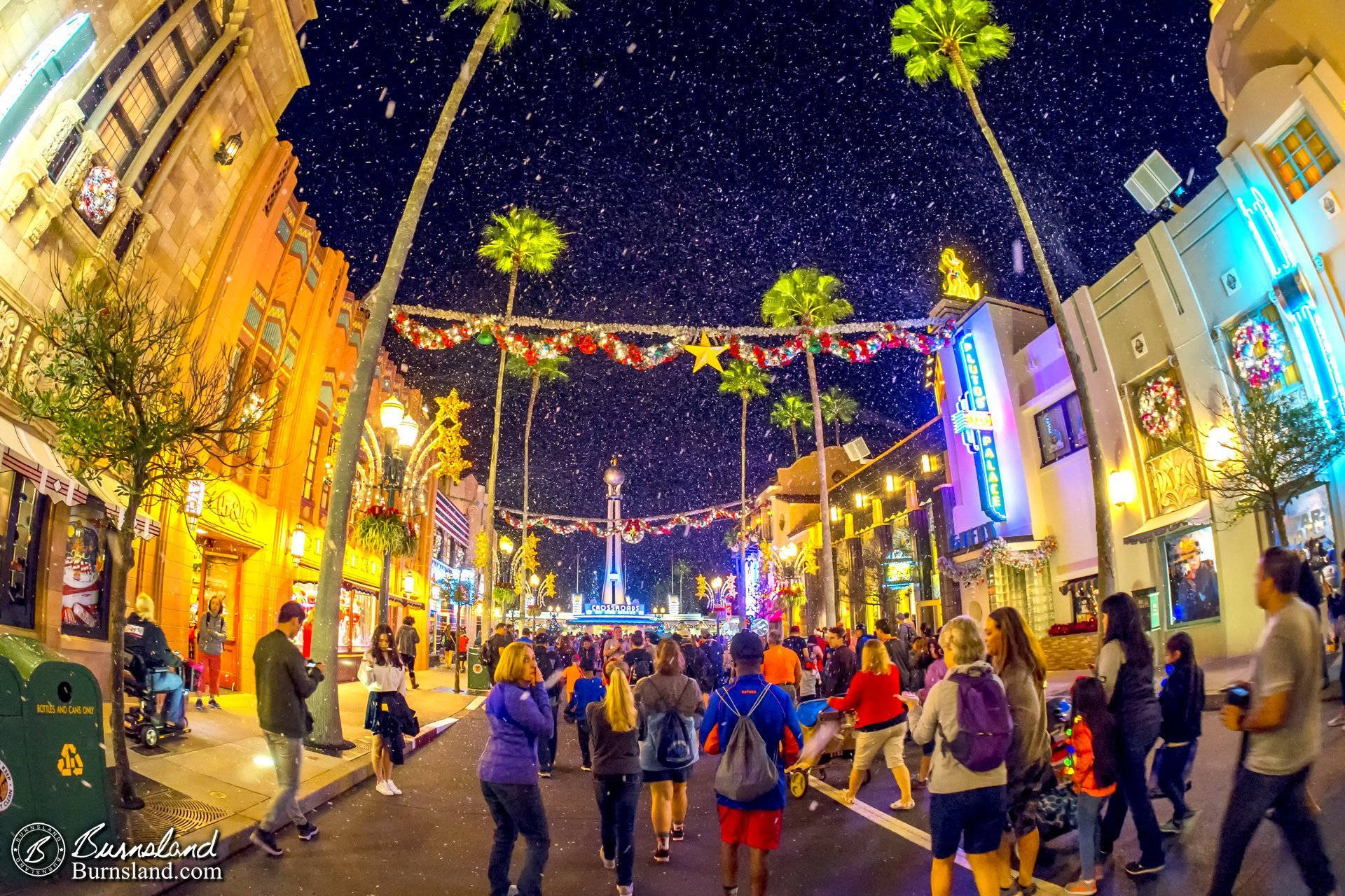 hollywood street 桌布 壁紙 — 充滿活力的夜間街景，棕櫚樹和節日燈飾下，人群在星空下漫步。