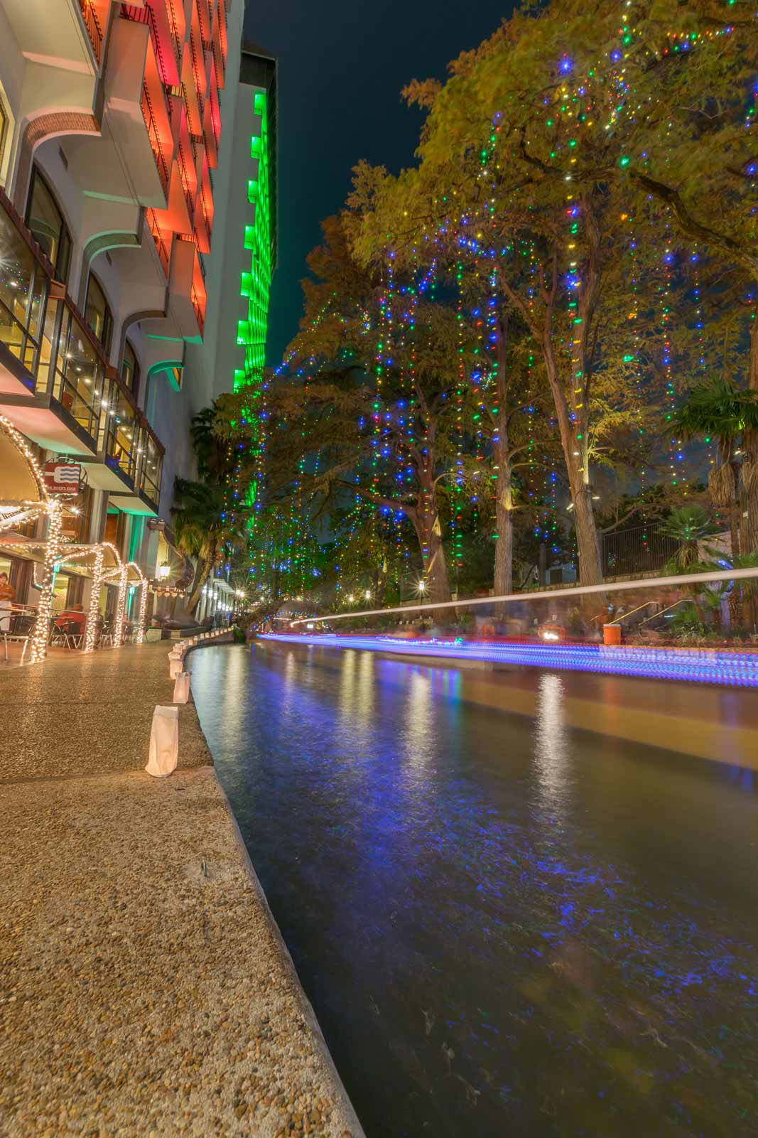 水 桌布 壁紙 — 充滿活力的夜間運河場景，色彩繽紛的串燈裝飾著樹木和建築物，倒映在水中。