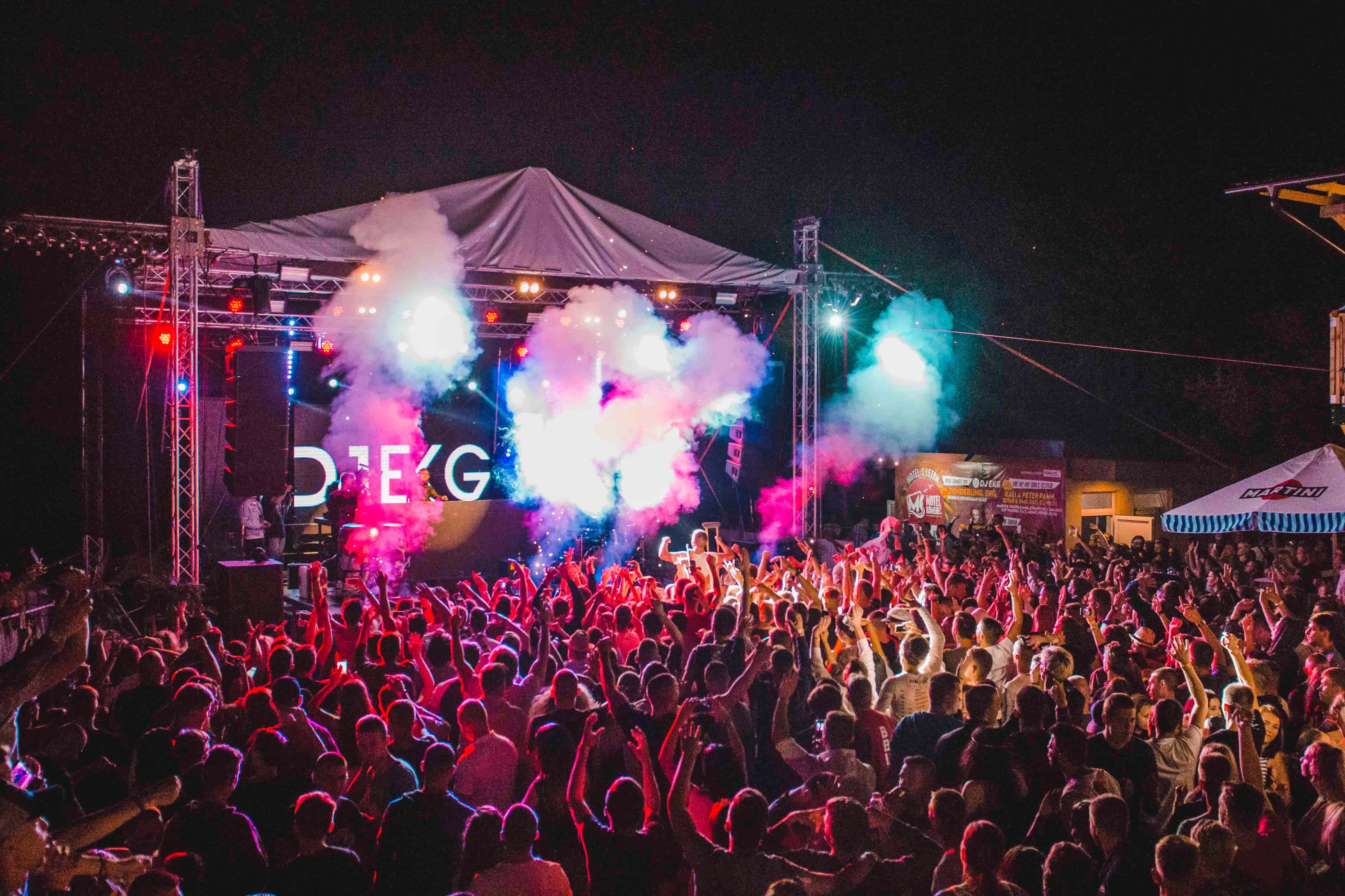 music festival 桌布 壁紙 — 充滿活力的夜間音樂會人群在粉紅色、藍色和白色煙霧及頻閃燈光籠罩的舞台下向前湧動。