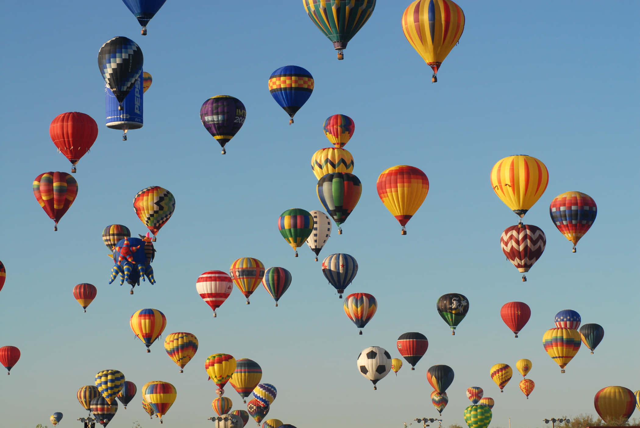 Balloon 桌布 壁紙 — 充滿活力的天空，數十個色彩繽紛的熱氣球漂浮在清澈的藍色大氣中。