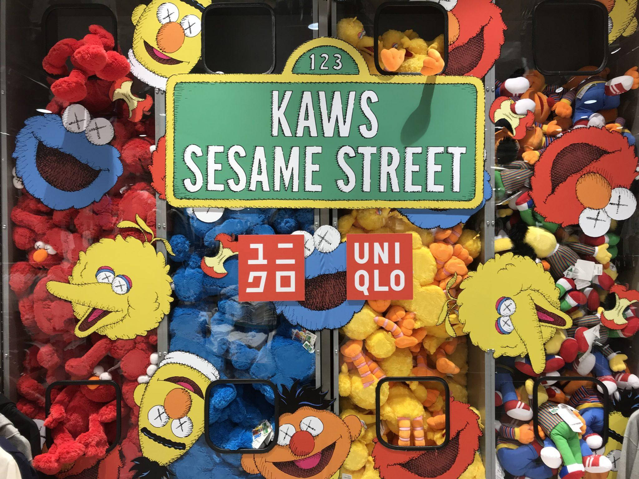 Uniqlo 桌布 壁紙 — 充滿活力的夾娃娃機，內有KAWS x 芝麻街絨毛玩具，標誌性角色眼睛被X掉。