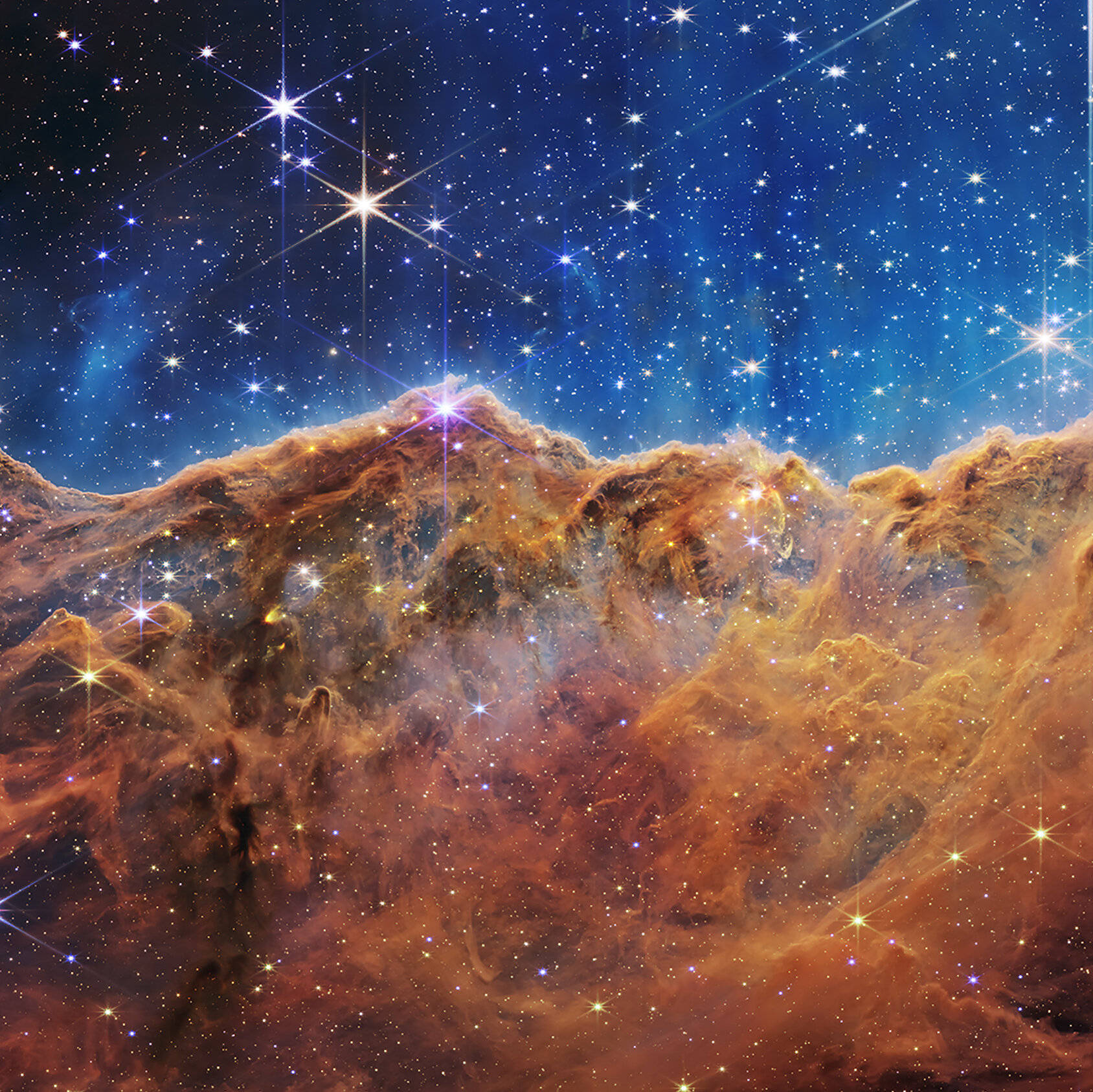 銀河 桌布 壁紙 — 充滿活力的宇宙星雲，帶有發光的橙色雲朵和閃爍的星星，背景是深藍色太空。