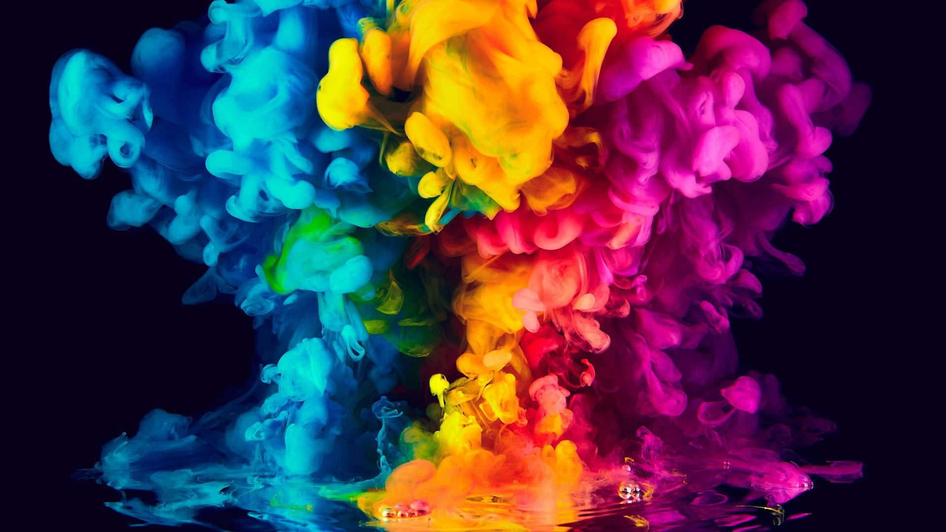 Abstract Colorful 桌布 壁紙 — 充滿活力的彩虹墨水雲從水中向上爆炸，在黑色背景上形成動態的抽象飛濺。