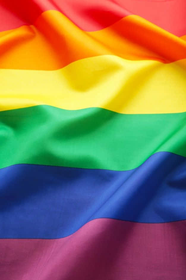 Pride Flag 桌布 壁紙 — 充滿活力的彩虹旗布料特寫，帶有流動的褶皺和豐富飽和的色彩。