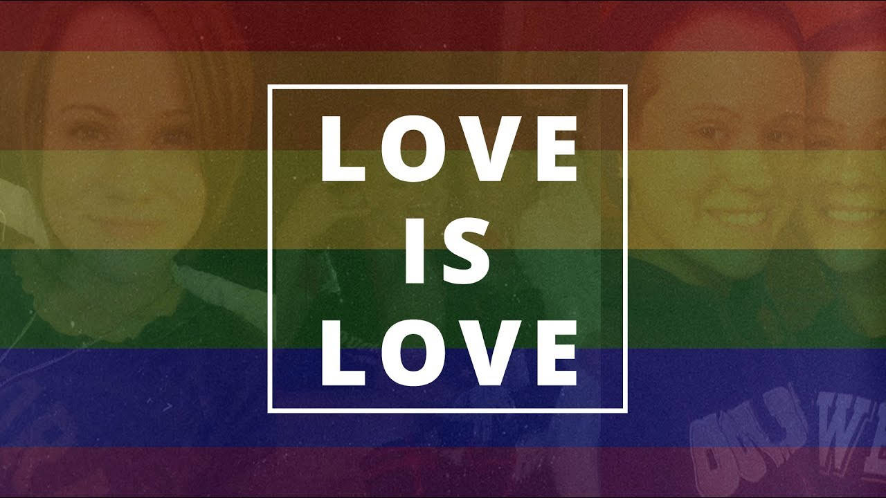 愛就是愛 桌布 壁紙 — 充滿活力的彩虹旗背景，粗體白色文字「LOVE IS LOVE」居中於褪色的微笑面孔之上。