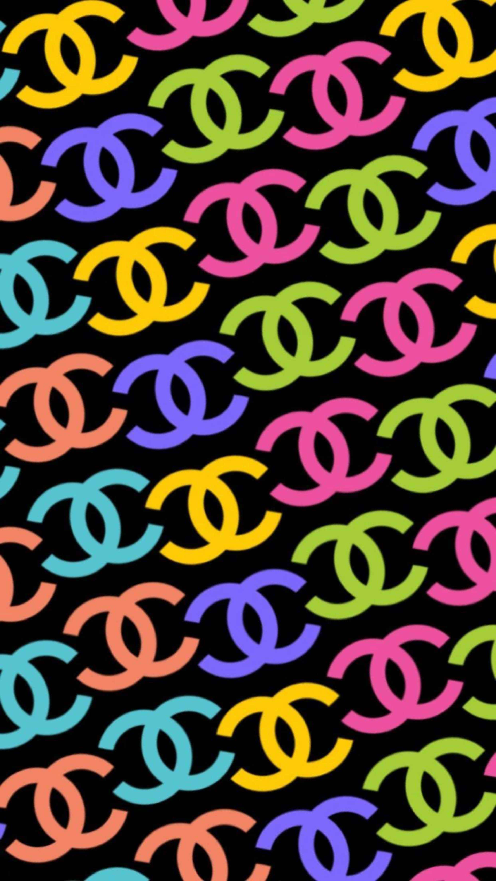 Chanel 桌布 壁紙 — 充滿活力的彩虹色 Chanel 標誌以對角線重複排列在純黑色背景上，形成大膽的圖案。