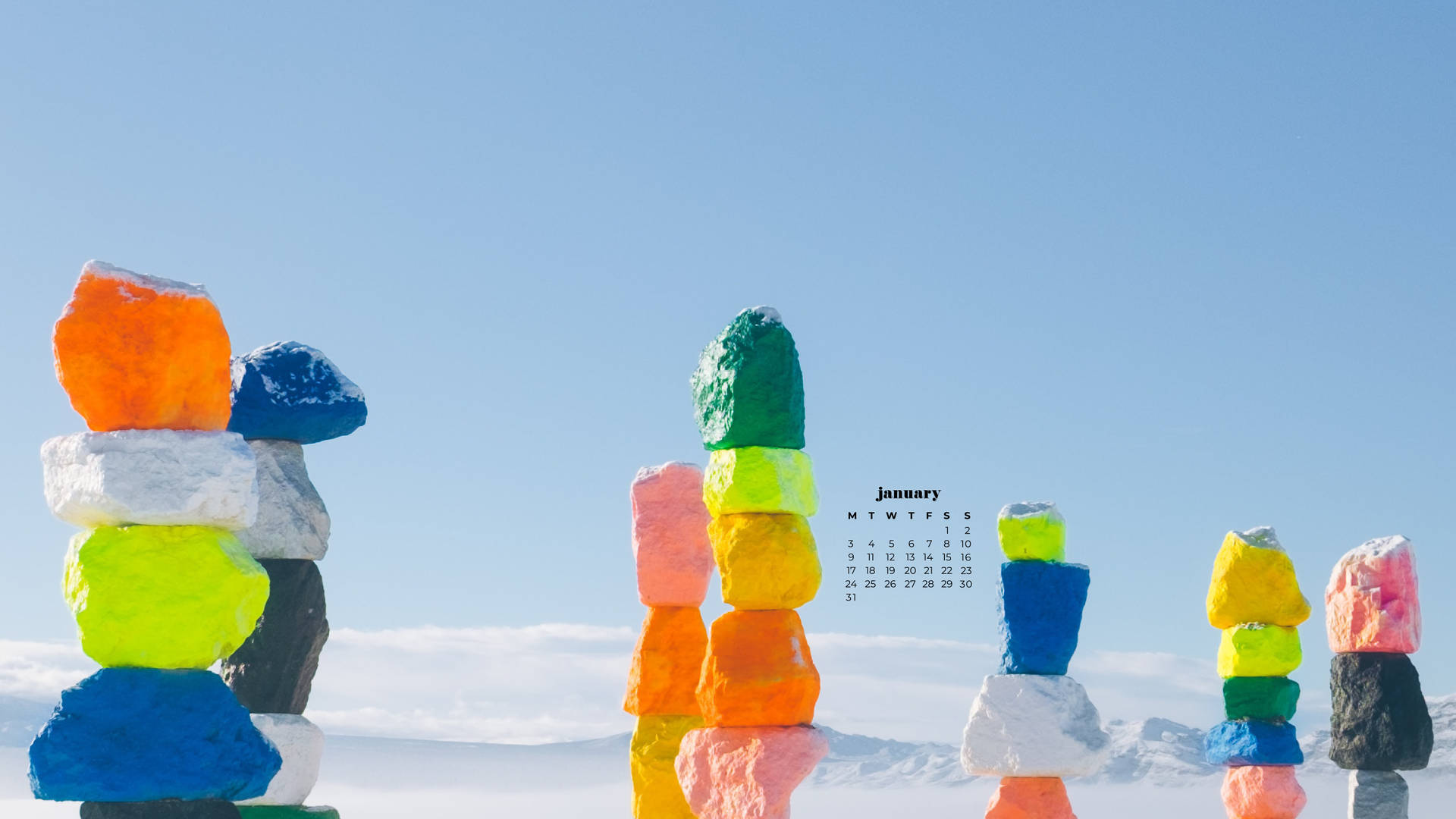 雪白山景中的彩色堆疊石塊與1月日曆。