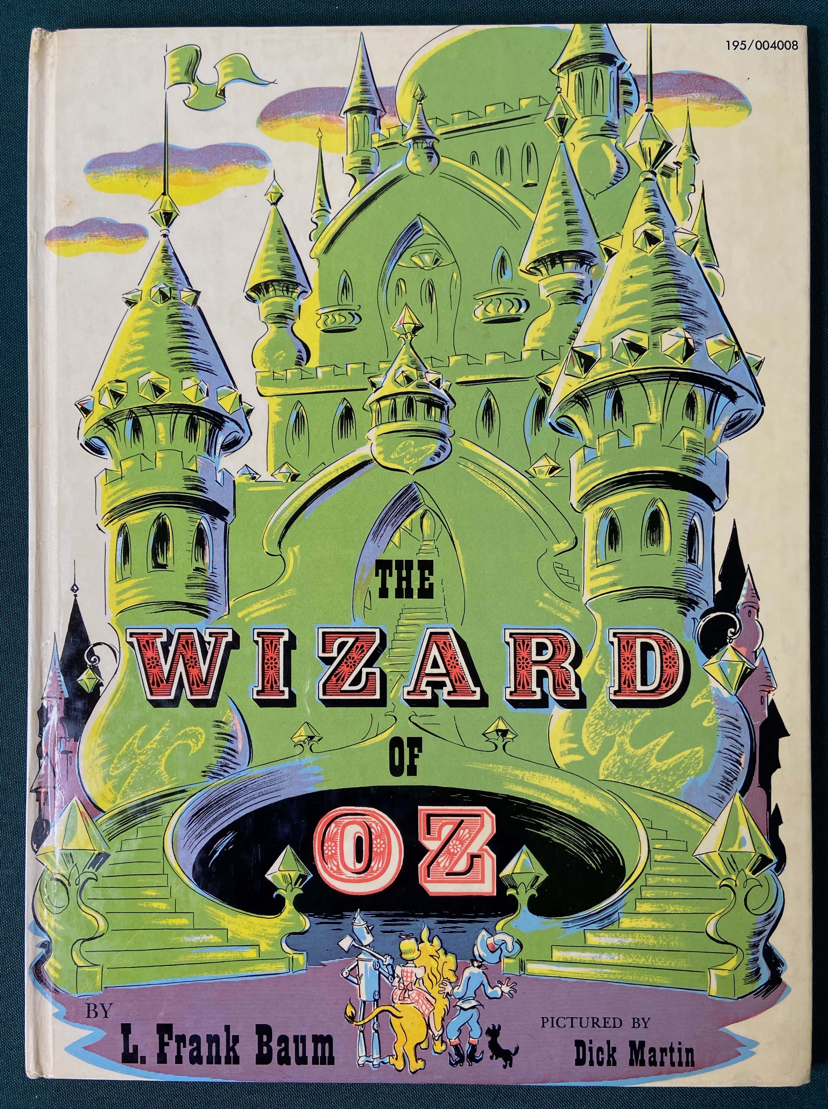 wizard of oz 桌布 壁紙 — 充滿活力的復古《綠野仙蹤》書籍封面，特色是綠色城堡，下方有角色，背景是色彩繽紛的天空。