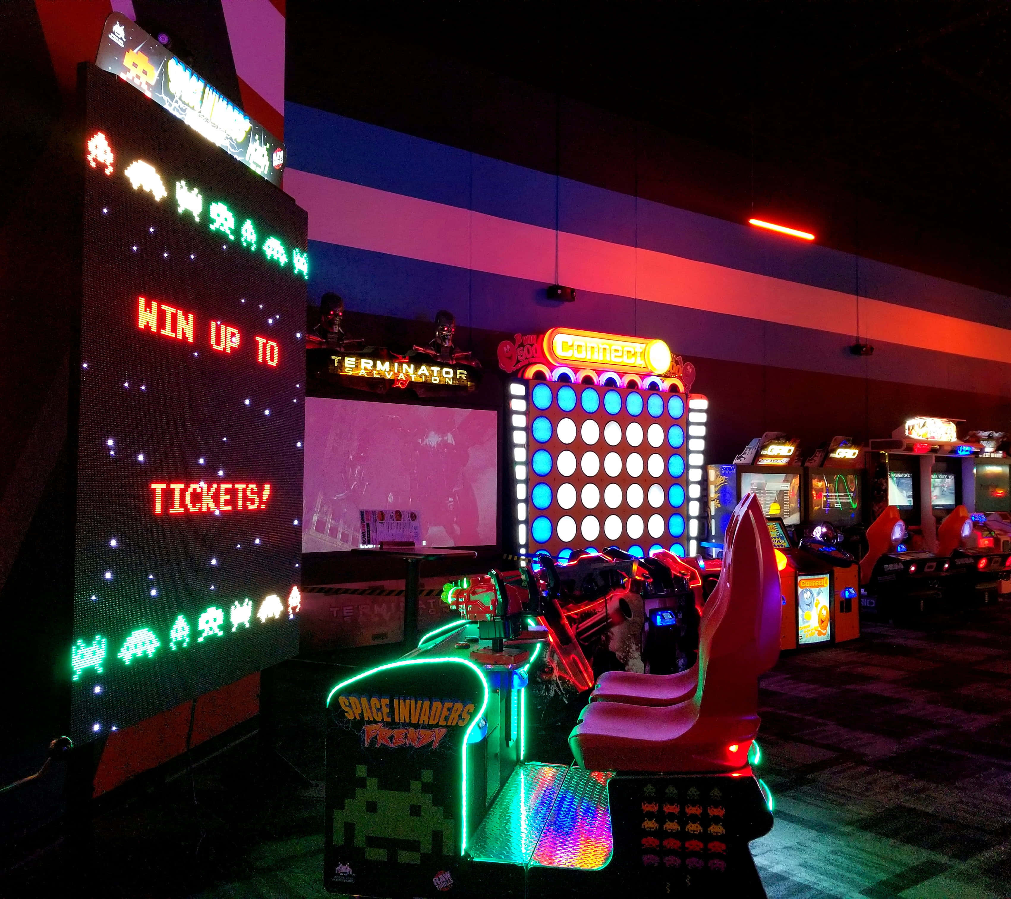 arcade 桌布 壁紙 — 充滿活力的復古街機在昏暗的遊戲廳中閃爍著霓虹燈光。