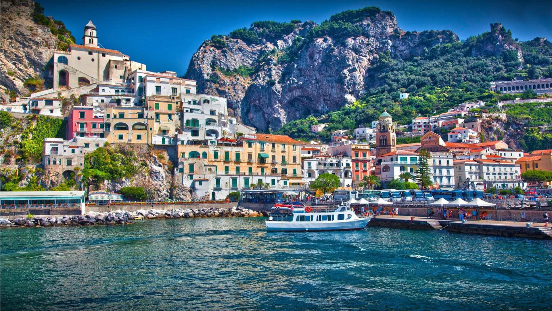Capri 桌布 壁紙 — 充滿活力的懸崖村莊，擁有粉彩建築和白色小船，在清澈藍天下的碧綠海水上。