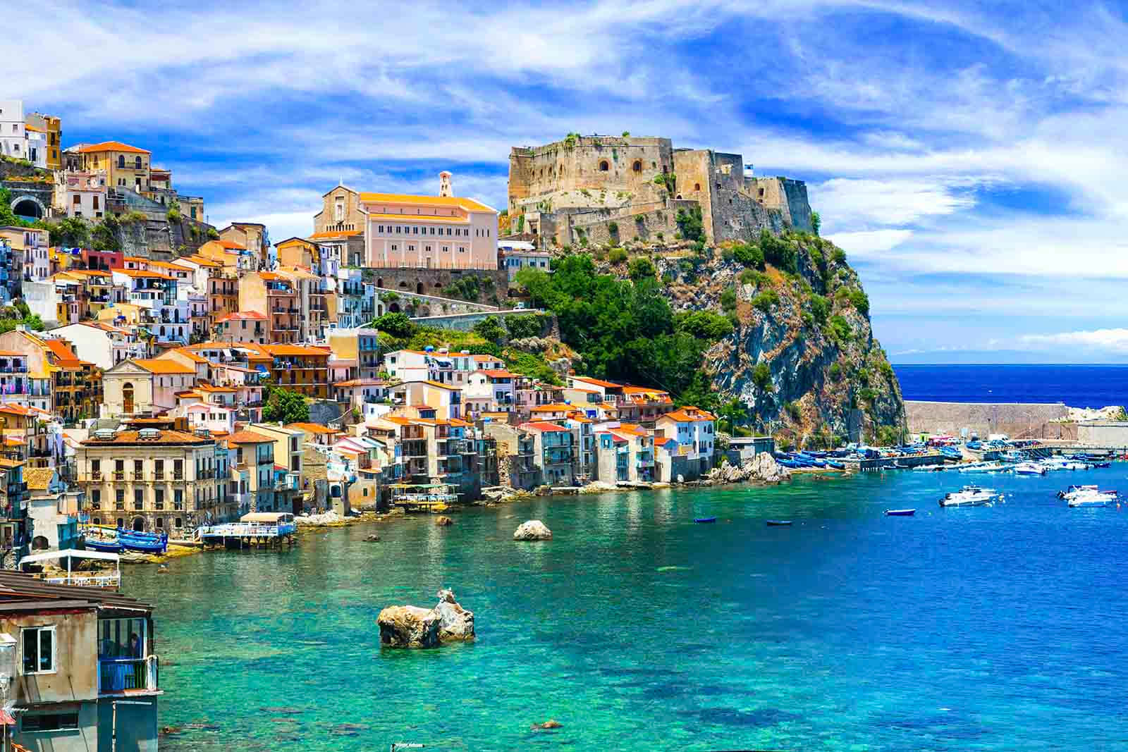 Italian 桌布 壁紙 — 充滿活力的懸崖村莊，擁有陶土屋頂和堡壘，俯瞰著點綴著船隻的碧綠海水。