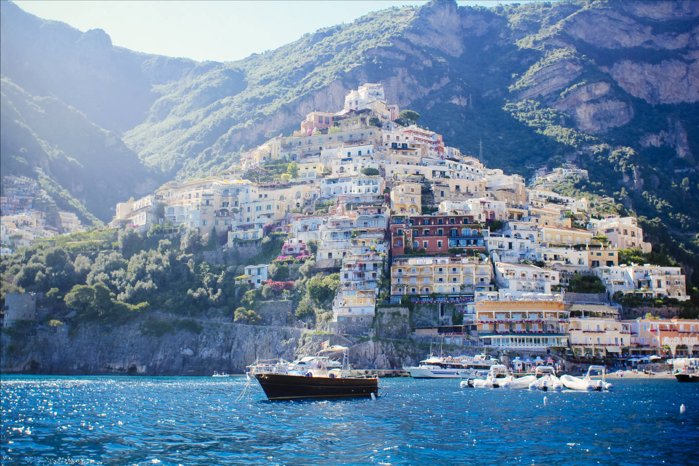 Capri 桌布 壁紙 — 充滿活力的懸崖村莊波西塔諾沿著陽光明媚的山坡傾瀉而下，匯入波光粼粼的藍色大海，下方停泊著船隻。