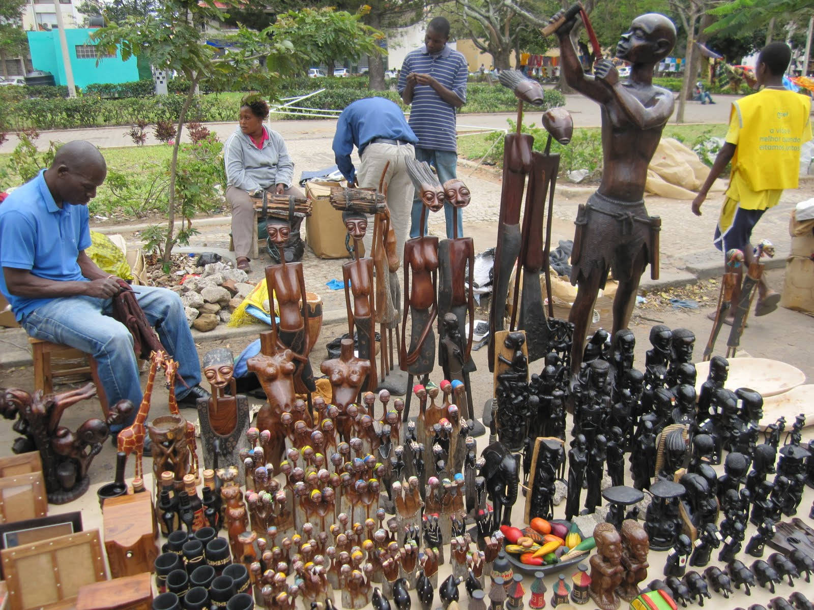 Mozambique 桌布 壁紙 — 充滿活力的戶外市場攤位在明亮的日光下展示精緻的木雕和雕塑。