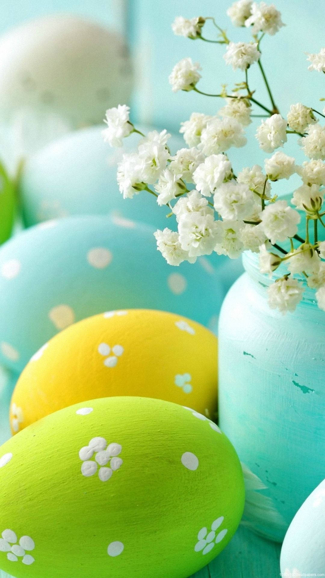 Easter iPhone 桌布 壁紙 — 充滿活力的手繪復活節彩蛋，帶有白色花卉和圓點圖案，旁邊放著一個藍綠色罐子，裡面插著精緻的白色滿天星。