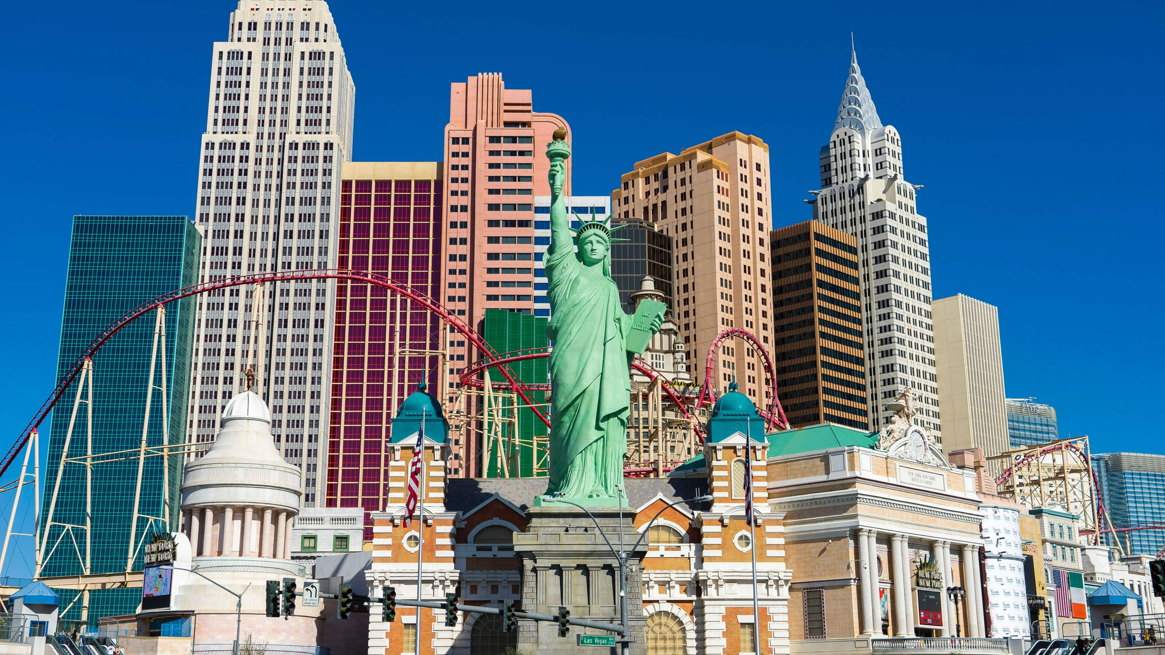 Las Vegas 桌布 壁紙 — 充滿活力的拉斯維加斯天際線，包括自由女神像複製品、雲霄飛車和高聳的飯店，在晴朗的藍天下。