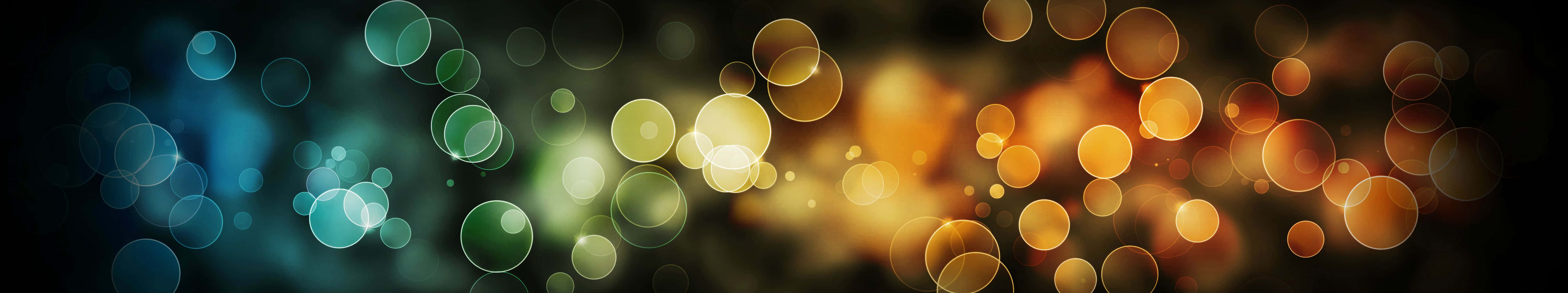 Bokeh 桌布 壁紙 — 充滿活力的散景圓圈在深色漸變背景上散發著溫暖的金色和冷色調的青色光芒。