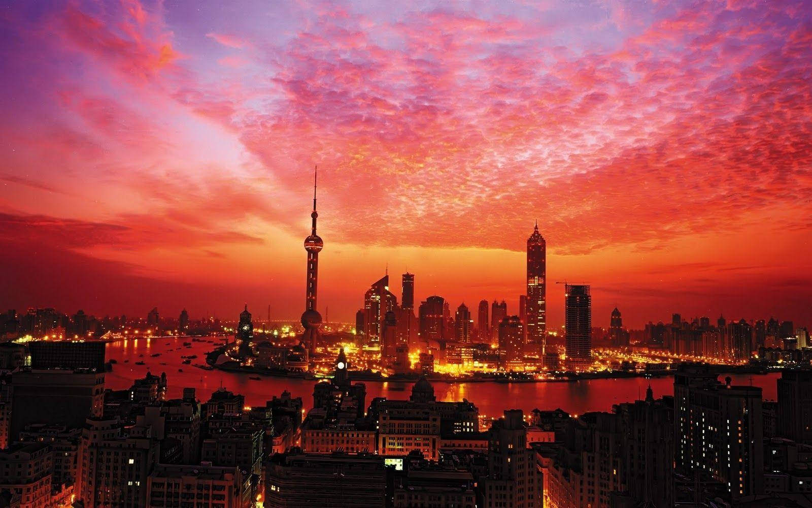 日落 桌布 壁紙 — 充滿活力的日落將上海天際線染成火紅和粉紅色，城市燈光倒映在黃浦江上。