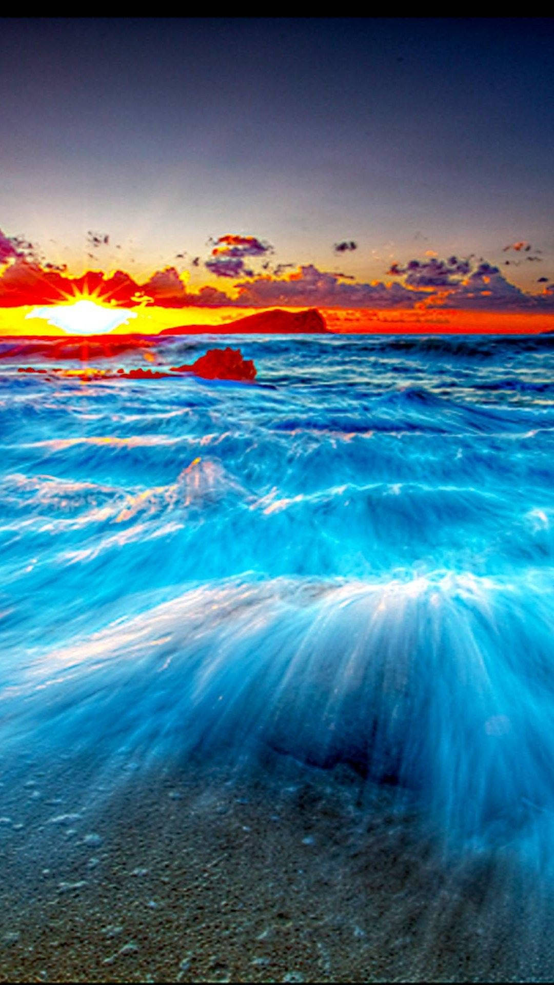 Ocean iPhone 桌布 壁紙 — 充滿活力的日落將天空染成火熱的橙色和紅色，海浪拍打沙灘，閃爍著藍色的海水。