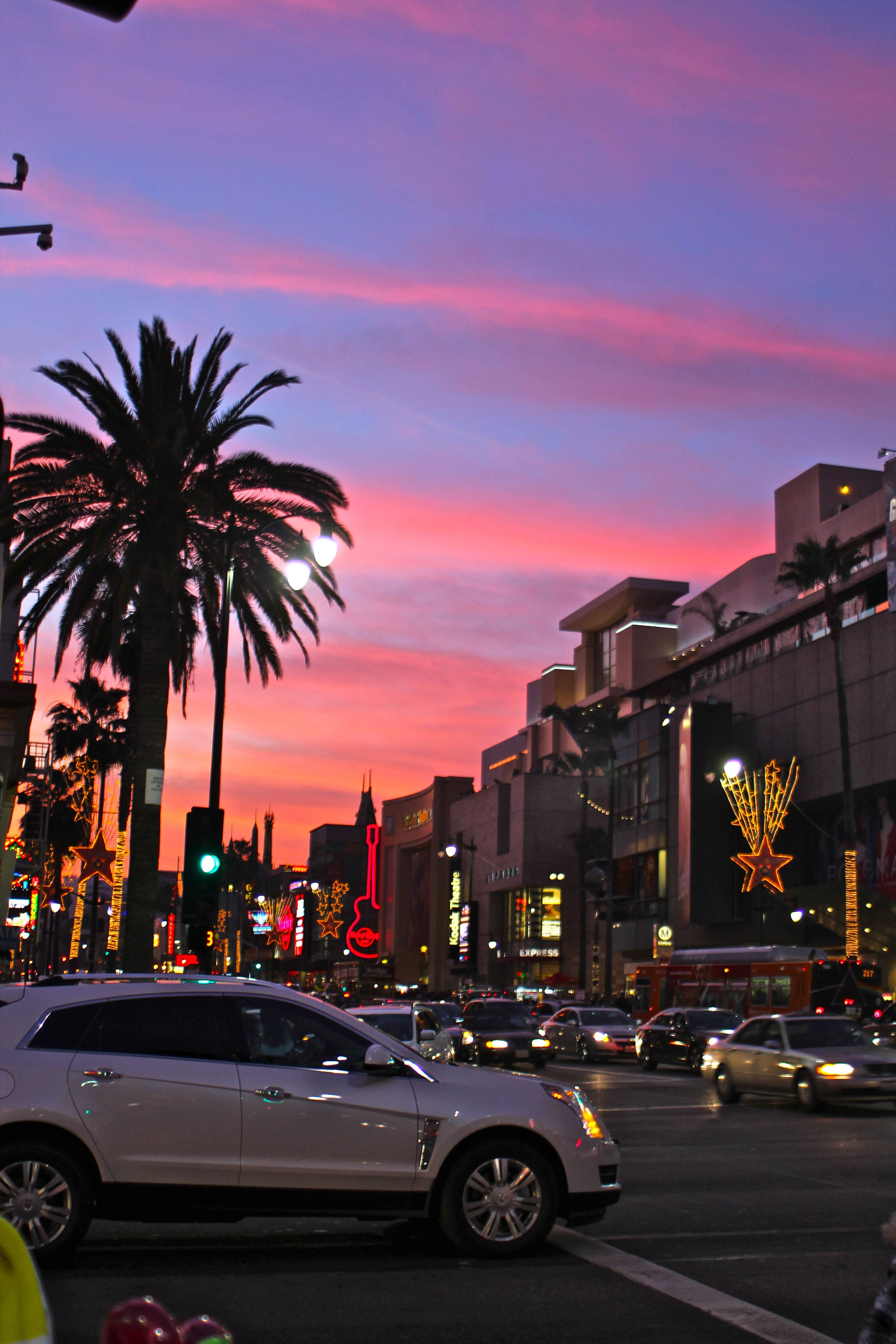 Boulevard 桌布 壁紙 — 充滿活力的日落將好萊塢星光大道染成粉紅色和紫色，棕櫚樹和閃爍的霓虹燈照亮了繁華的街道。