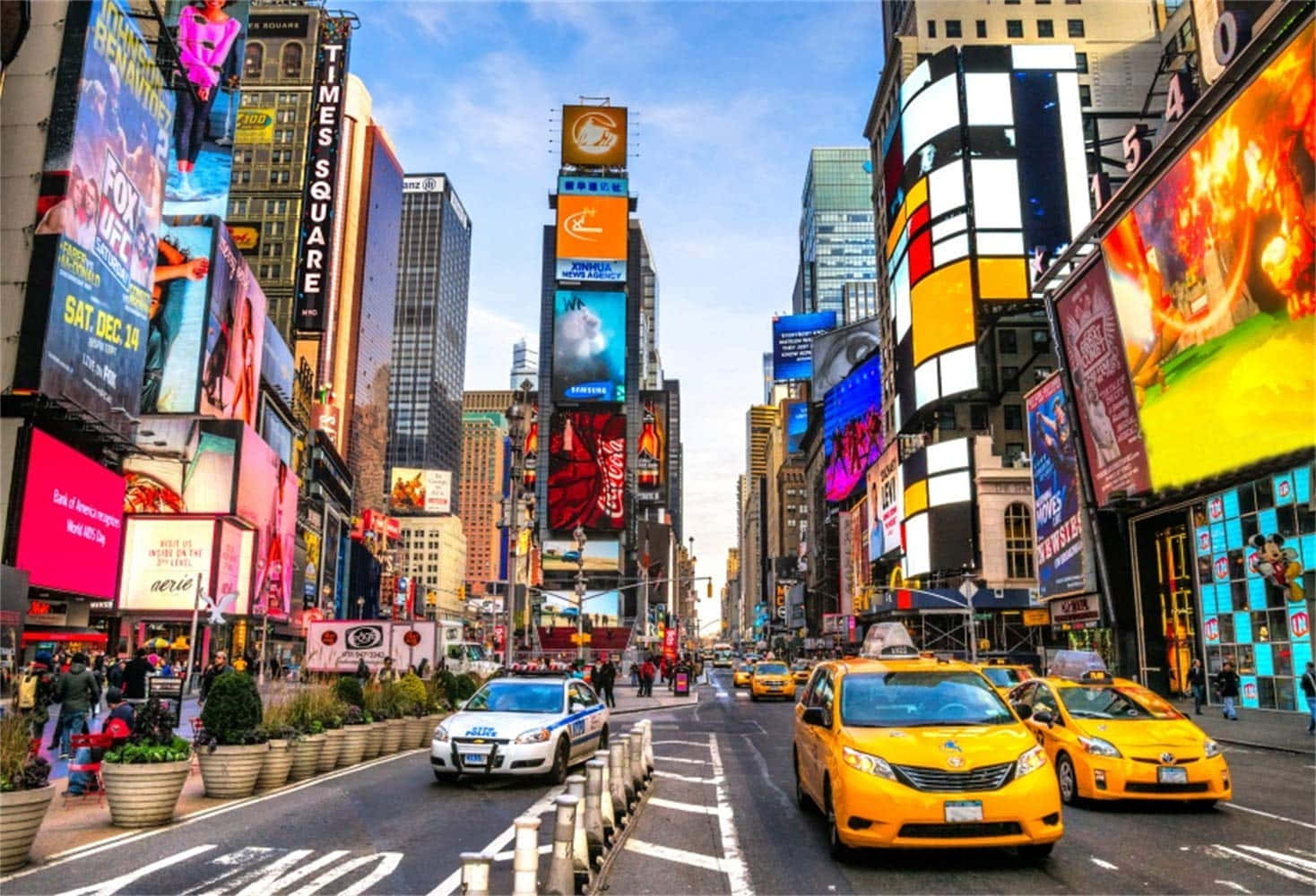New York 桌布 壁紙 — 充滿活力的時代廣場，高聳的廣告牌、霓虹燈和黃色計程車在清澈的藍天下熙熙攘攘。