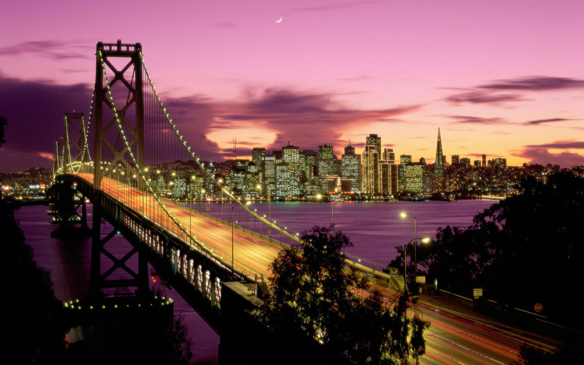 San Francisco HD 桌布 壁紙 — 充滿活力的暮色城市景觀，一座發光的吊橋橫跨水面，車流形成光帶，新月掛在洋紅色的天空中。