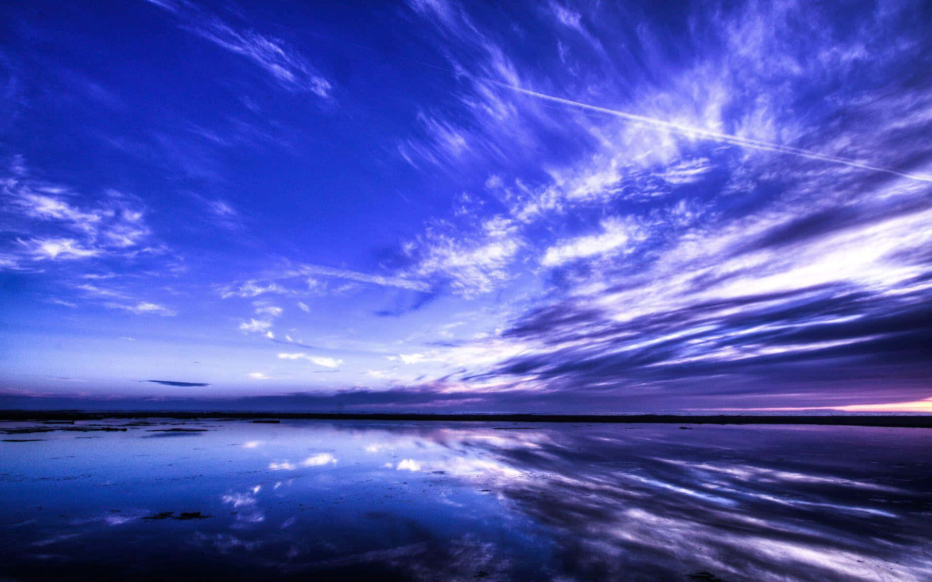 Beautiful Sky 桌布 壁紙 — 充滿活力的暮色天空，帶有紫色和藍色條紋的雲彩，完美地倒映在平靜如鏡的水面上。