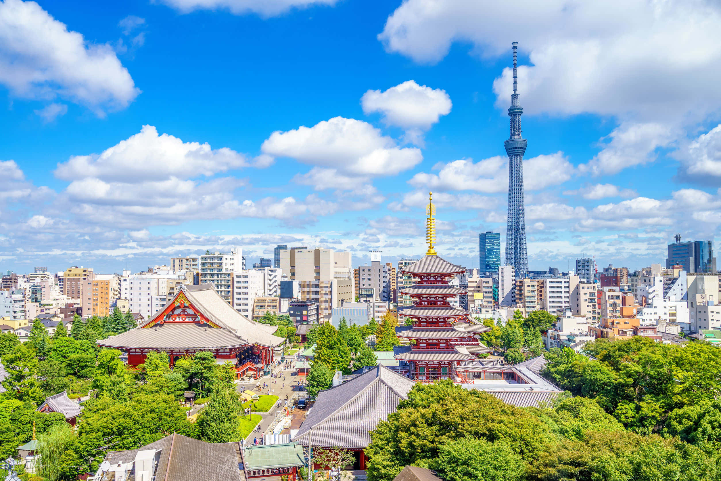東京 桌布 壁紙 — 充滿活力的東京天際線，以傳統紅色寺廟屋頂和標誌性的晴空塔為特色，在明亮的藍天和蓬鬆的白雲下。