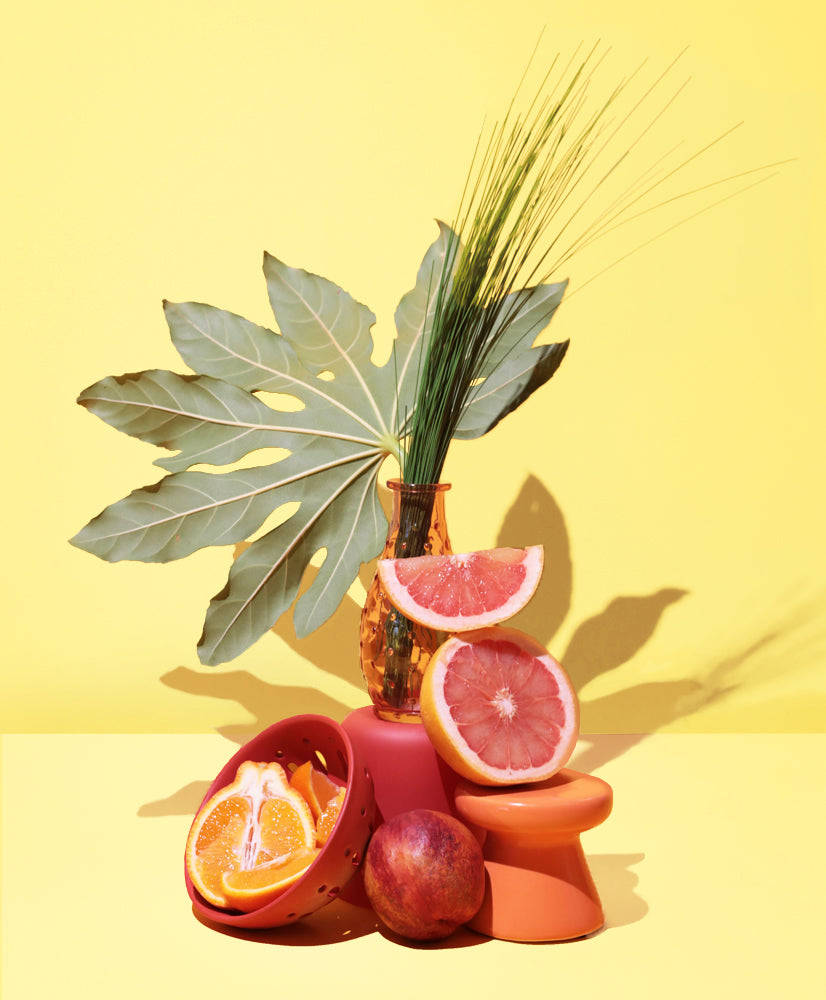 Fruits 桌布 壁紙 — 充滿活力的柑橘切片和熱帶葉子排列在赤陶容器中，以純黃色背景襯托。