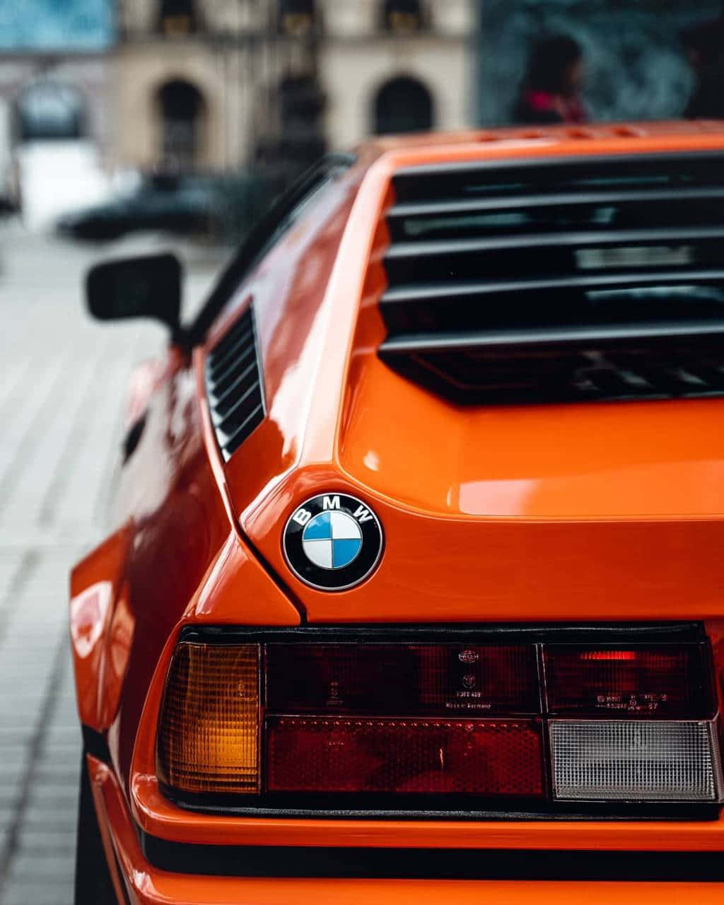 橙色BMW M1跑車城市街道後視圖 — BMW 動圖 壁紙