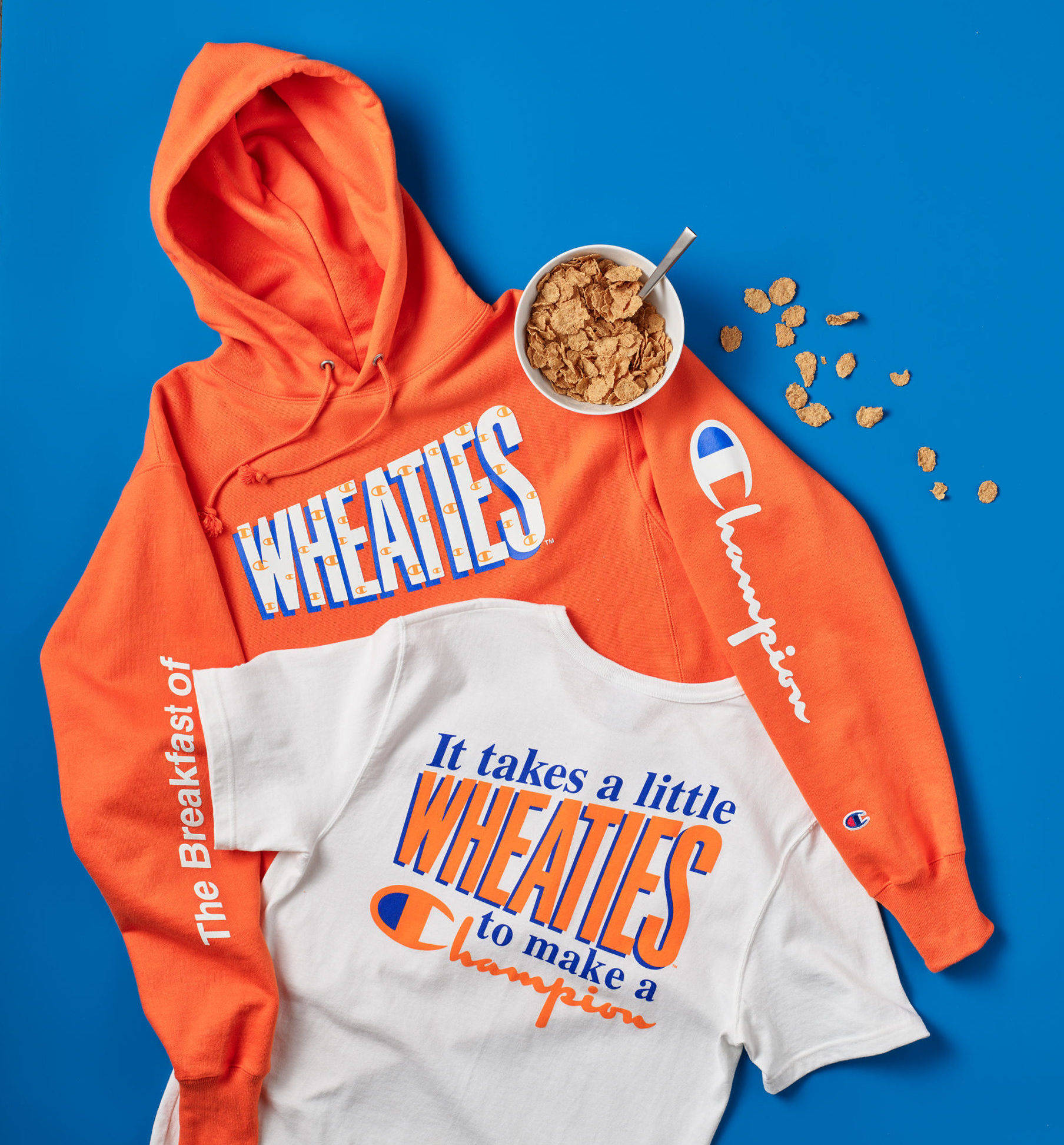 Champion 桌布 壁紙 — 充滿活力的橙色和白色Champion Wheaties服裝平放，搭配一碗麥片，置於大膽的藍色背景上。