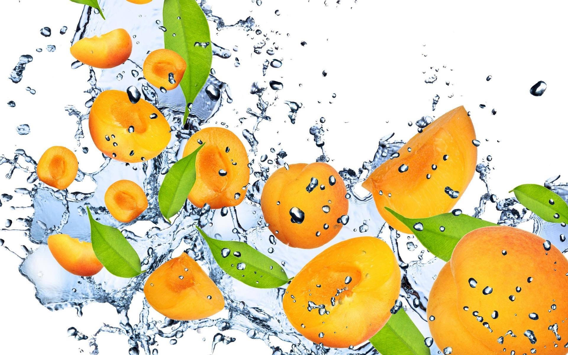 Fruits 桌布 壁紙 — 充滿活力的橙色杏片和綠葉在純白背景下，穿過清澈水花的動態飛濺。