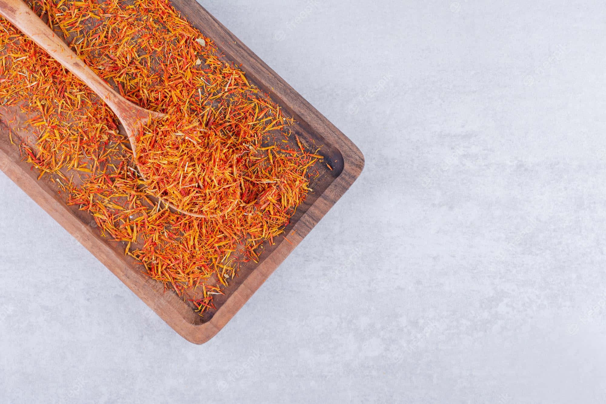 Saffron 桌布 壁紙 — 充滿活力的橙色番紅花絲放在木托盤中，搭配一個相配的勺子，置於淺灰色紋理表面上。