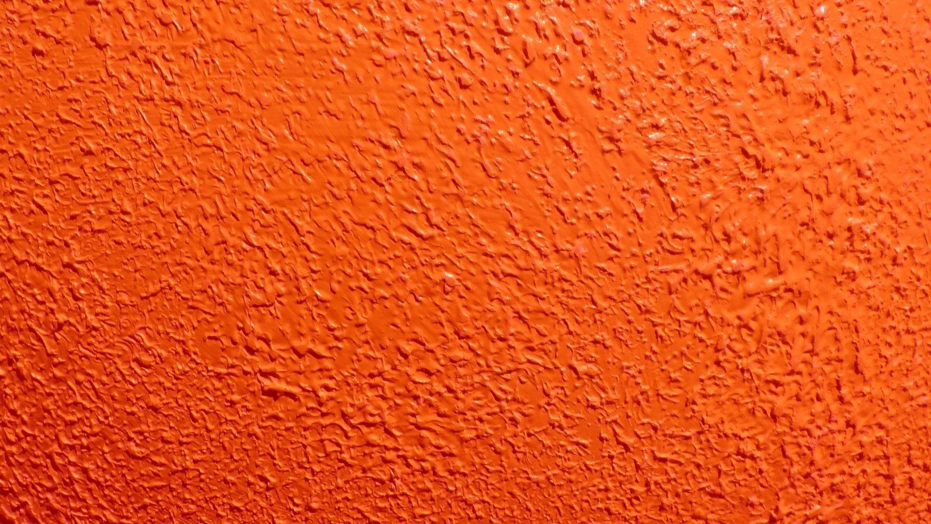 Orange 桌布 壁紙 — 充滿活力的橙色紋理牆壁，表面粗糙不均勻，在均勻光線下帶有細微高光。