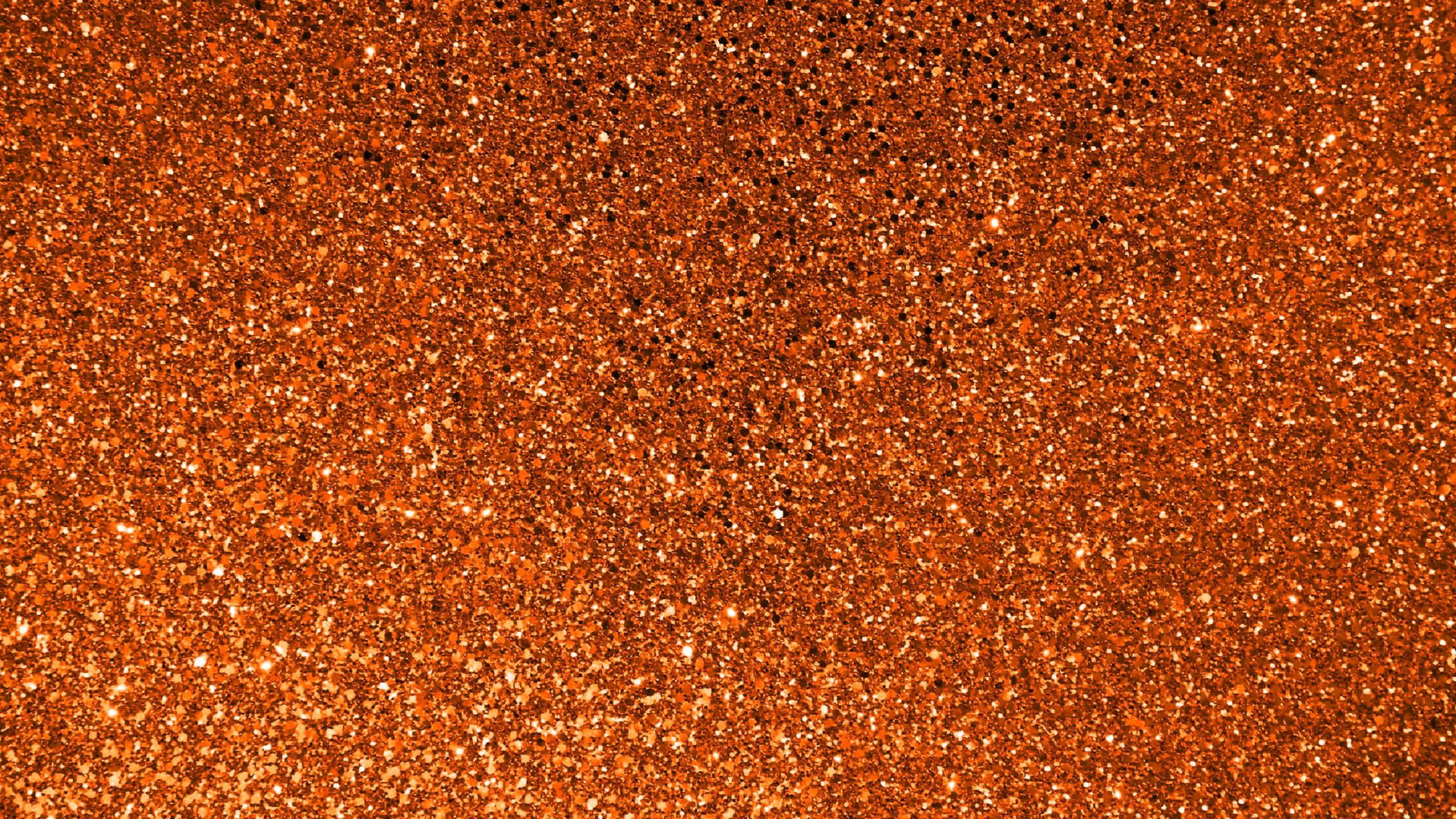 Orange Glitter 桌布 壁紙 — 充滿活力的橙色閃粉特寫，帶有閃爍亮點和深色斑點，營造出紋理閃爍的表面。