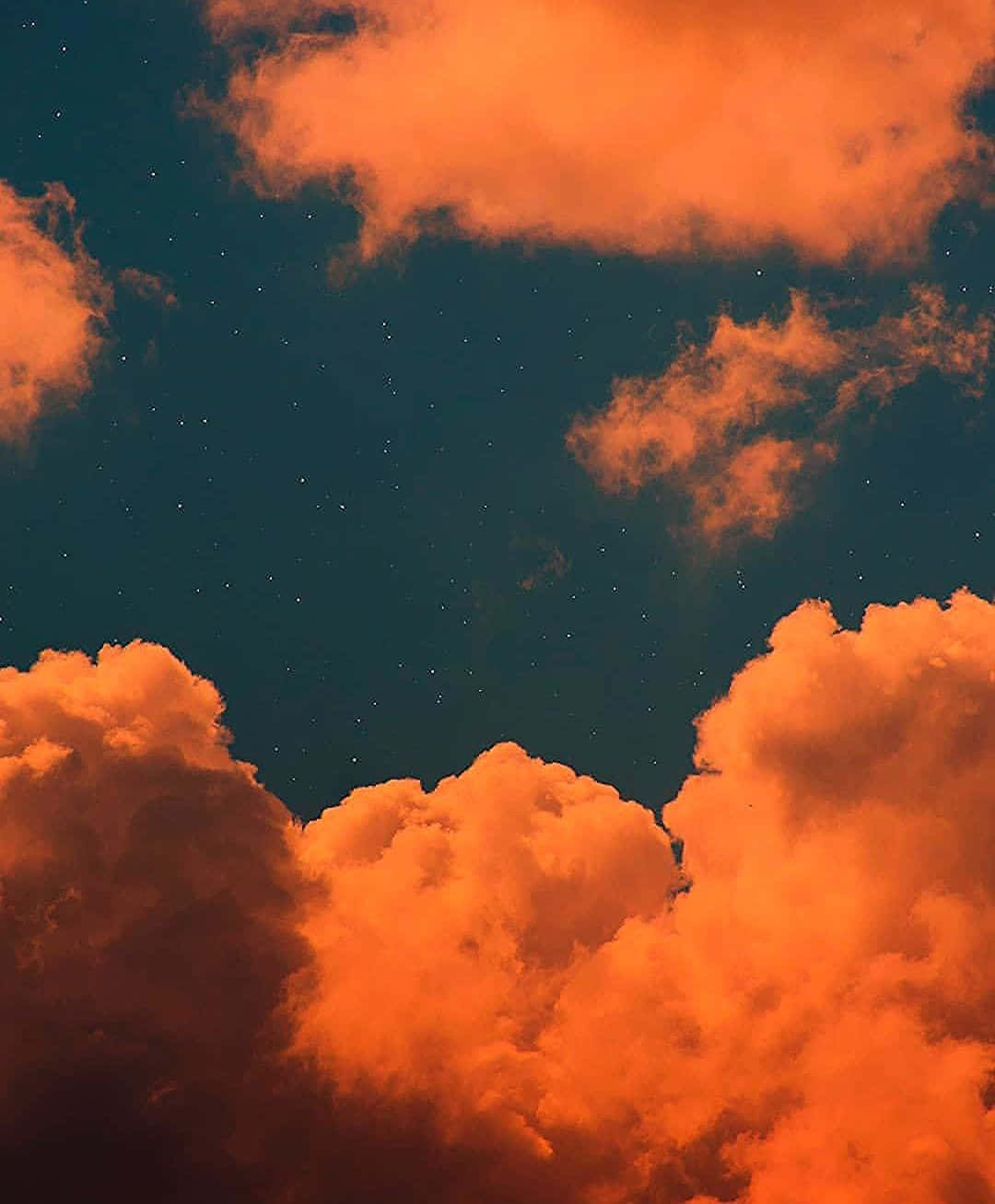 Cloud Aesthetic 桌布 壁紙 — 充滿活力的橙色雲朵在深藍綠色夜空下發光，夜空點綴著閃爍的星星。