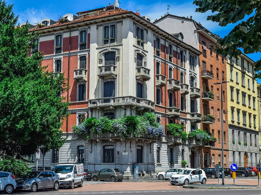 建築 桌布 壁紙 — 充滿活力的歐洲街景，色彩繽紛的歷史公寓建築點綴著陽台和盛開的植物，在明亮的藍天下。
